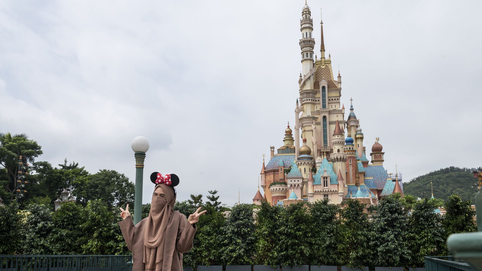 A person posing for a photo in front of the iconic Disney castle at Disneyland Resort in Hong Kong on Sept, 25.