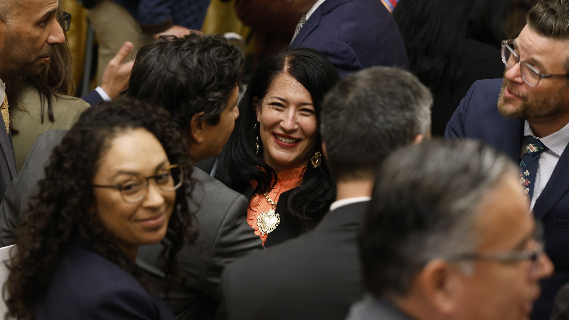 U.S. Poet Laureate Ada Limón smiles at the camera as she's surrounded by many people, none of whom are looking at the camera 