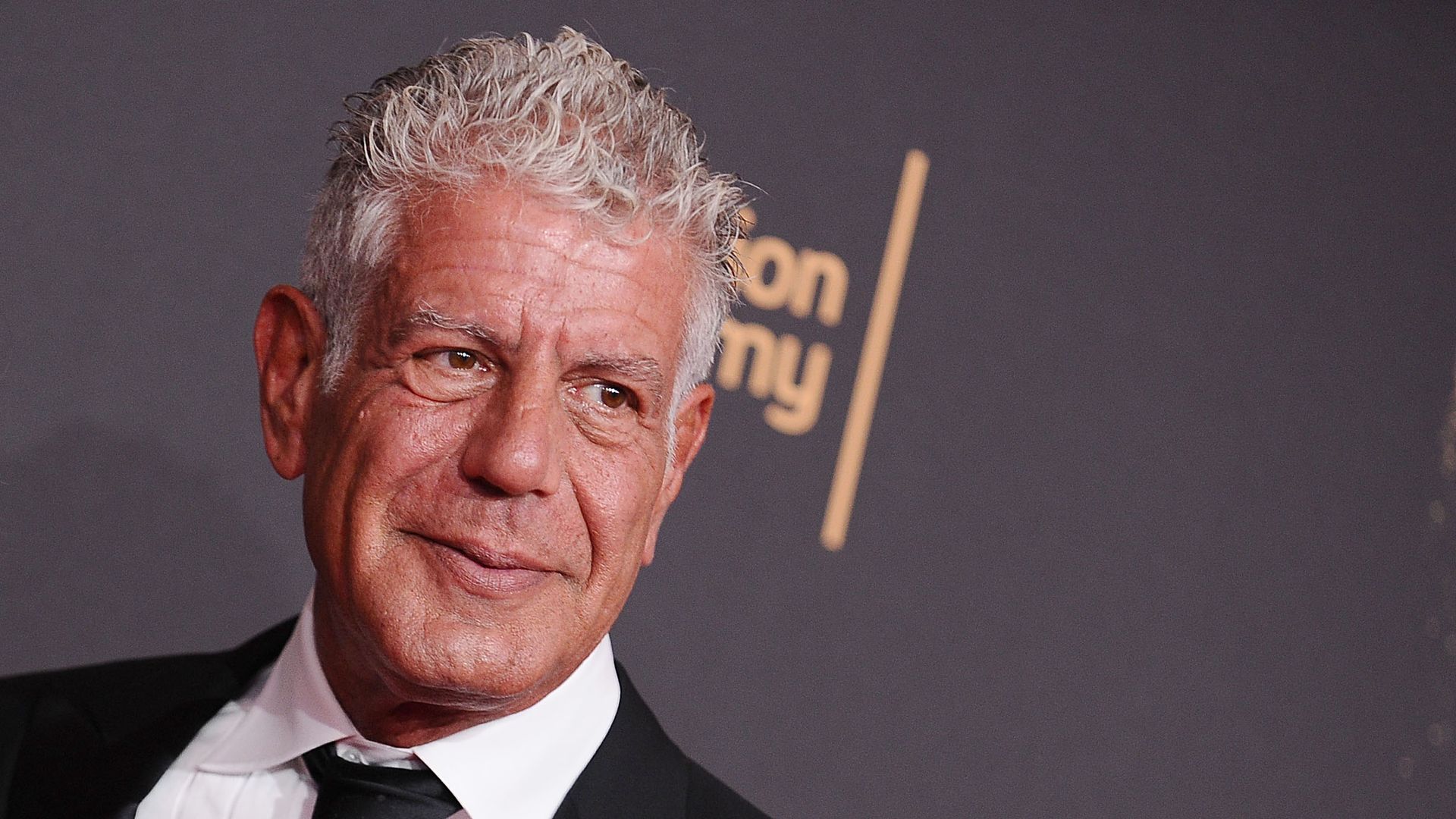 Anthony Bourdain smiles at the step-and-repeat at the 2017 Creative Arts Emmy Awards 