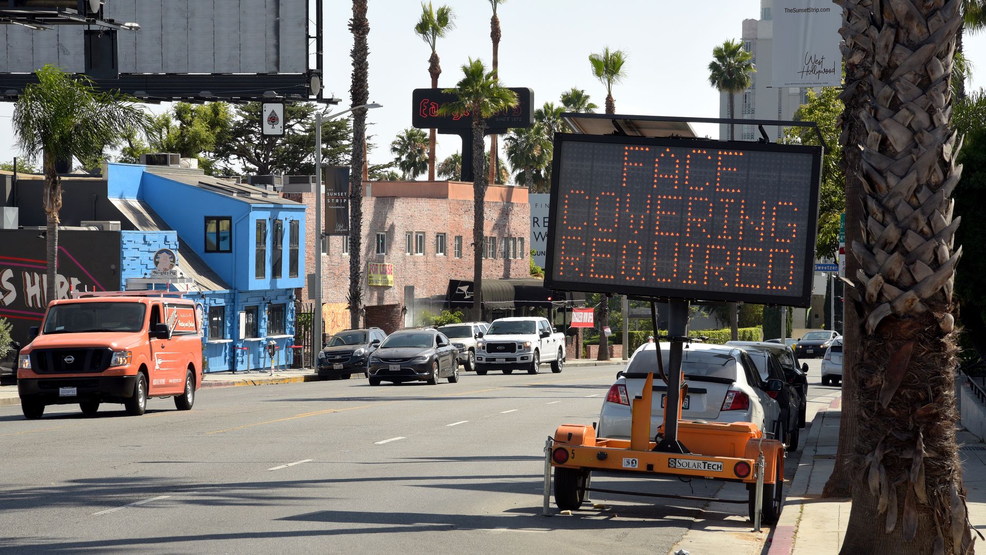 A COVID-19 warning sign on Sunset Boulevard says "Face mask required"