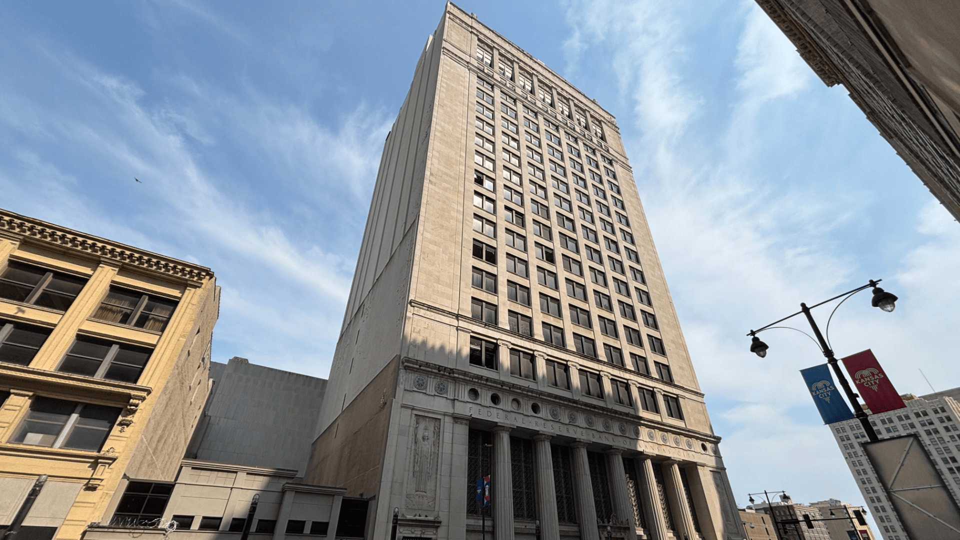 Four photos in a GIF show a tall building downtown with zoomed in images of broken out windows, cracked glass, and razor wire.