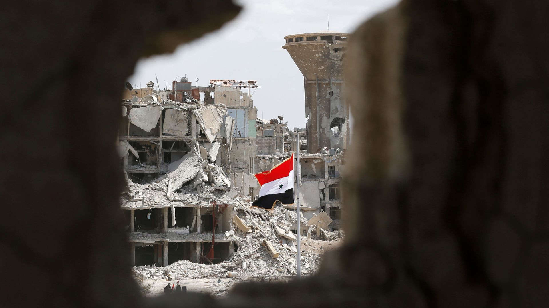 A Syrian flag flying amid rubble.