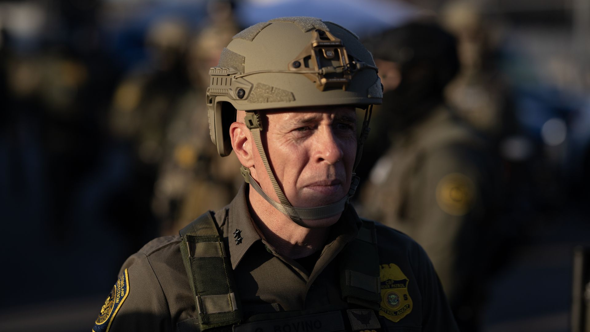 A close-up photo of the face of a man wearing tactical Border Patrol gear, including a helmet.
