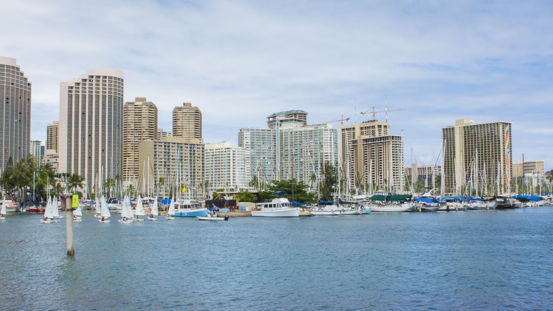 Honolulu Hawaii Oahu skyline from boat marina with sailboats school on small sailboats boating in Yacht Club. 