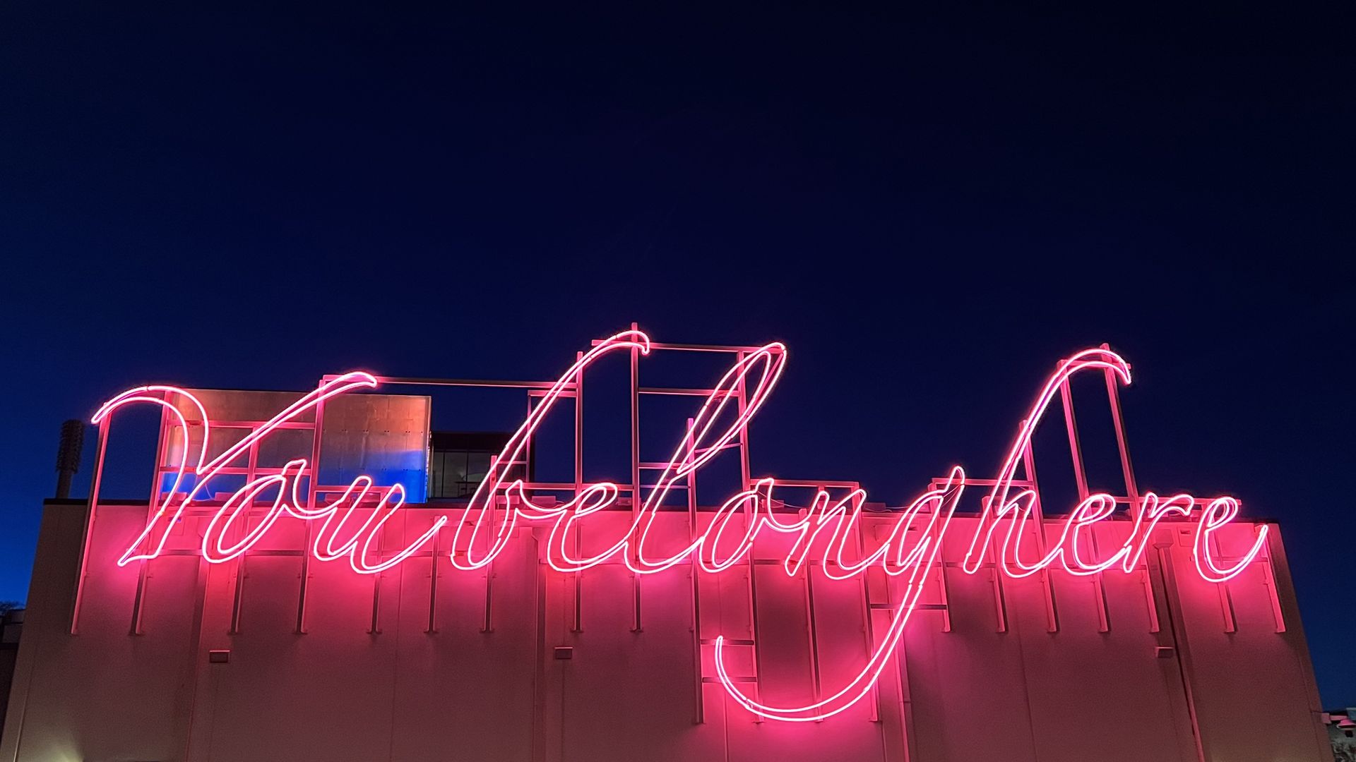 pink neon sign that reads in script "You belong here"