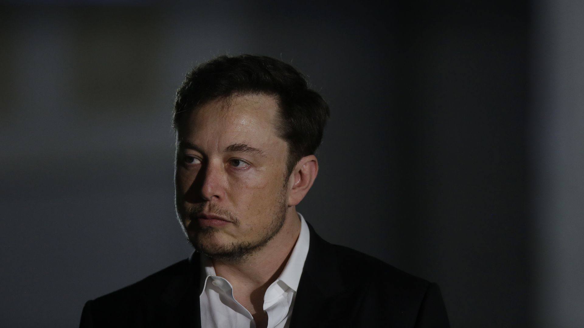 Close up of Elon Musk, who's wearing a serious expression 