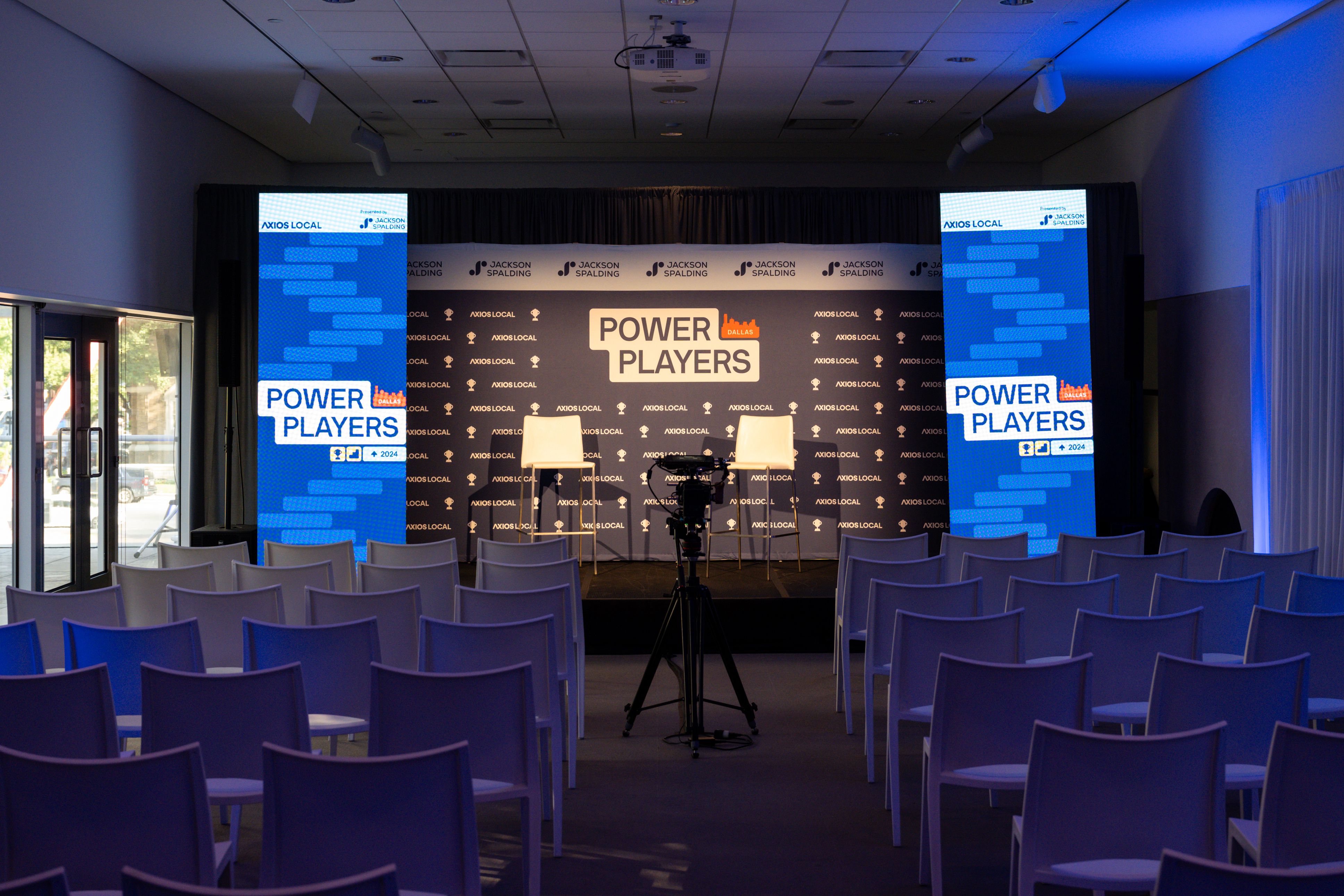 empty room with stage at front that reads power players and rows of empty chairs