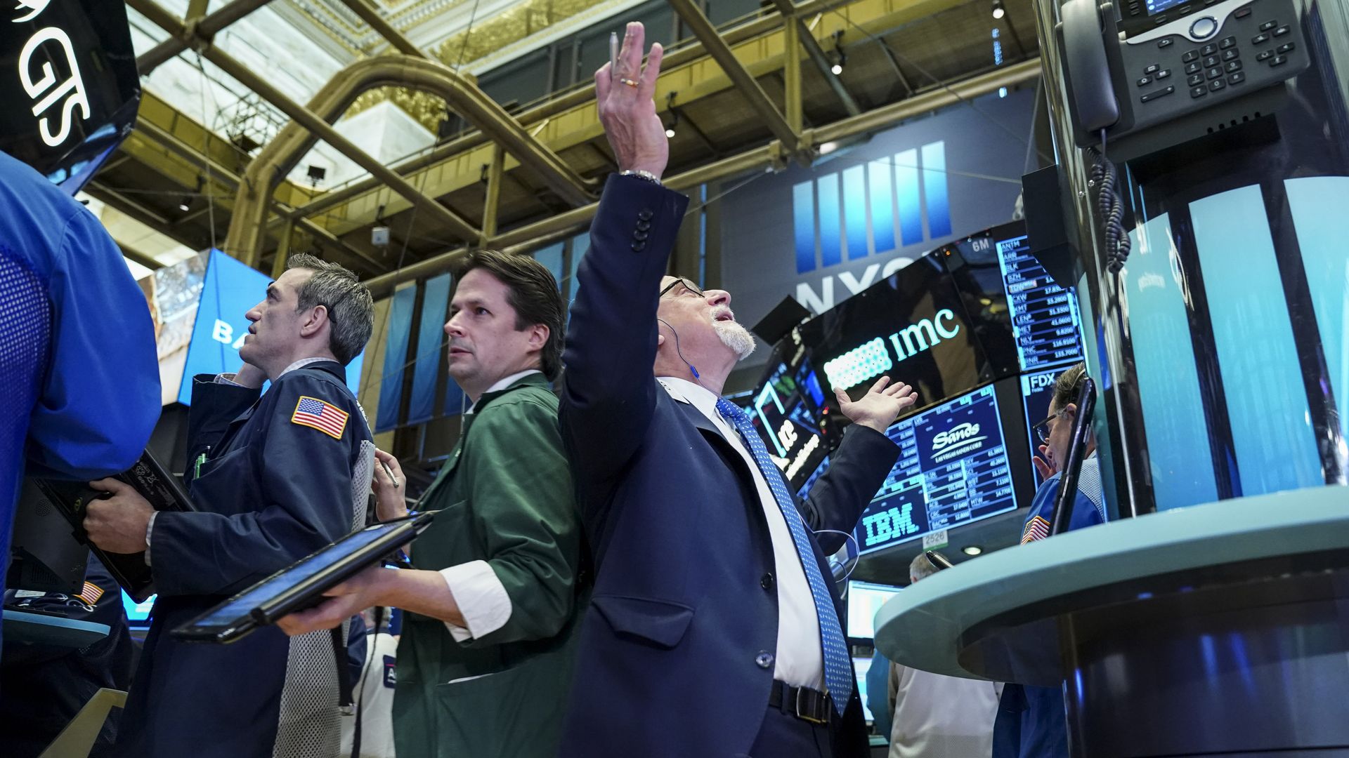 Traders and financial professionals work at the opening bell on the floor of the NYSE