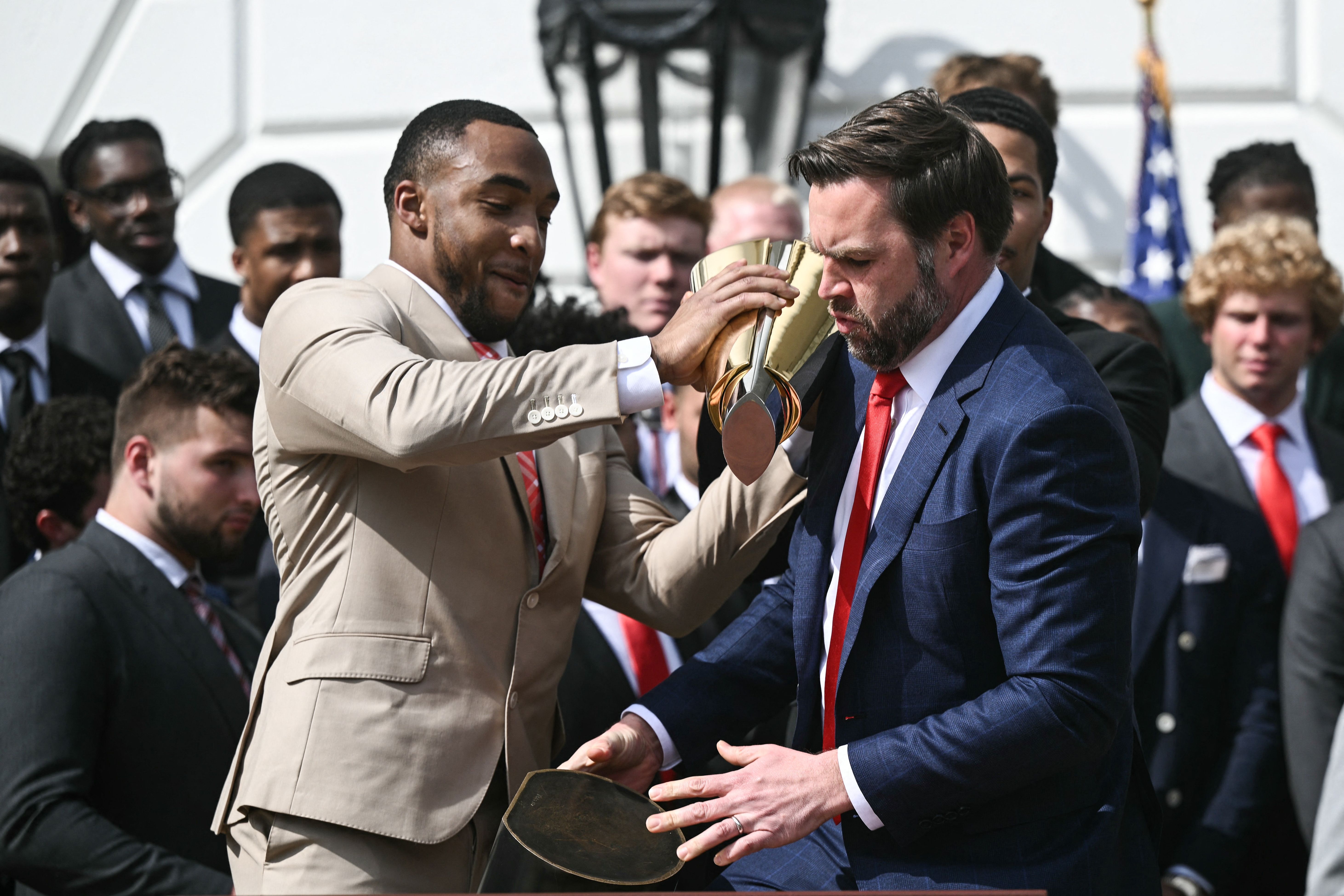 TreVeyon Henderson holds the College Football Playoff National Championship Trophy over U.S. Vice President JD Vance after it falls apart and separates.