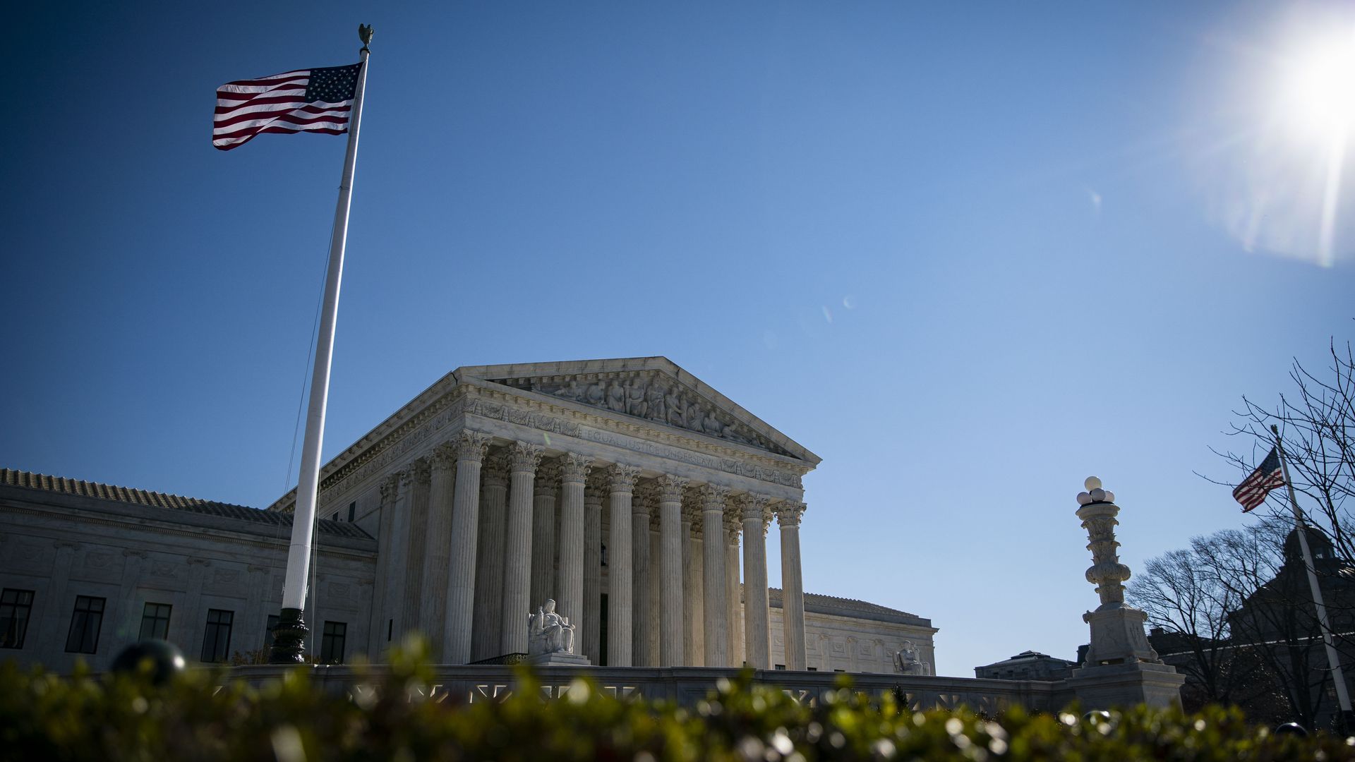 An image of the Supreme Court with an American flag flying on the left side of the frame