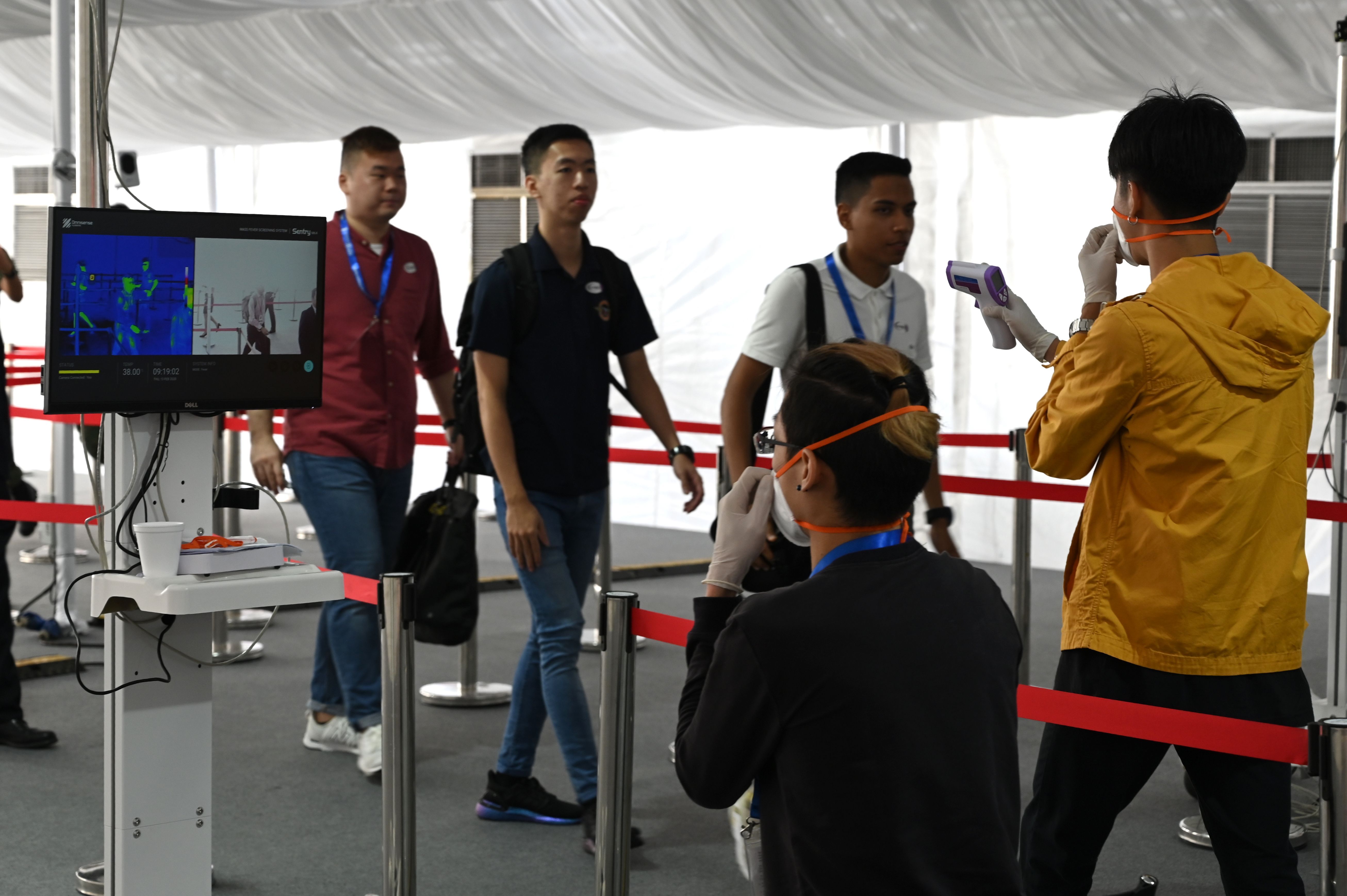 A medical staff member takes the temperature of visitors to the Singapore Airshow