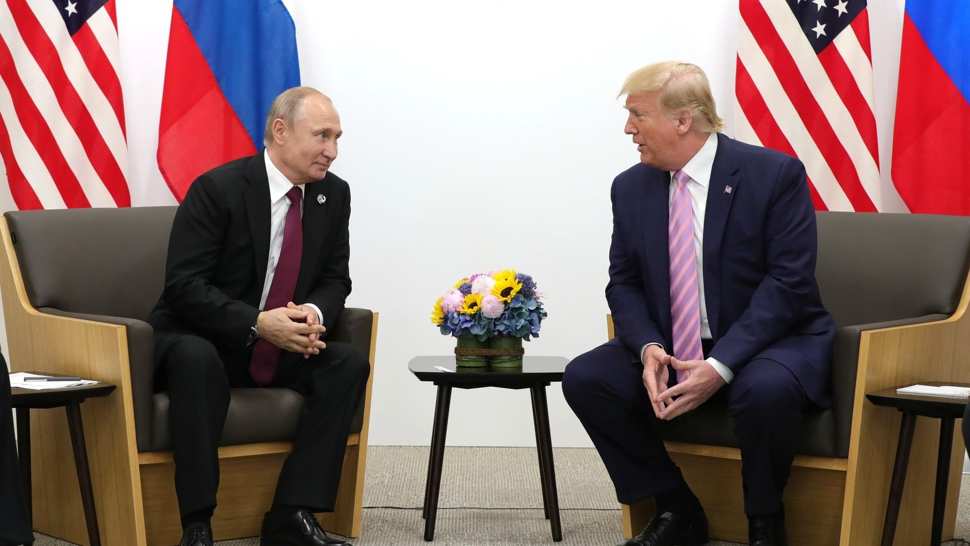 Vladimir Putin and Donald Trump speak to each other while seated