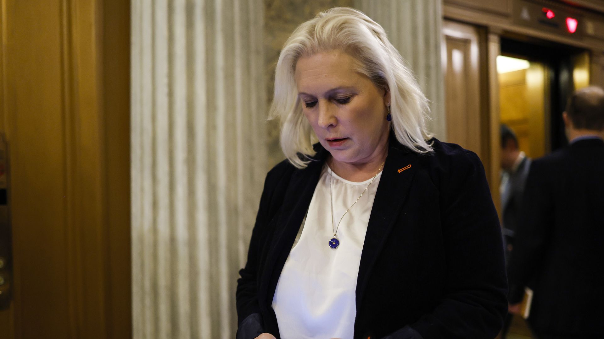 A Senator looking at her cell phone while walking through a congressional building. 
