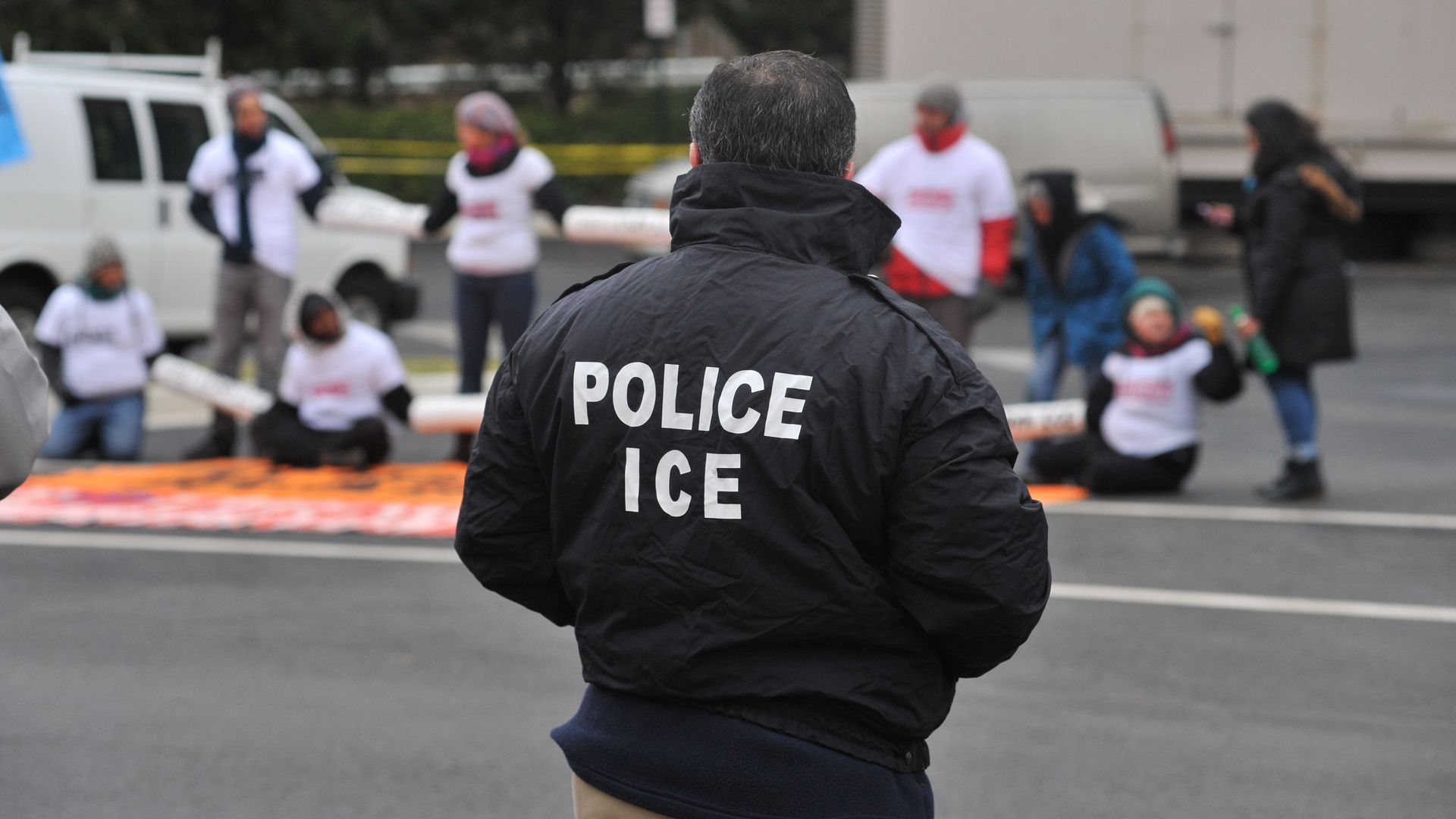 Person stands with a black jacket with white lettering that says "Police ice"