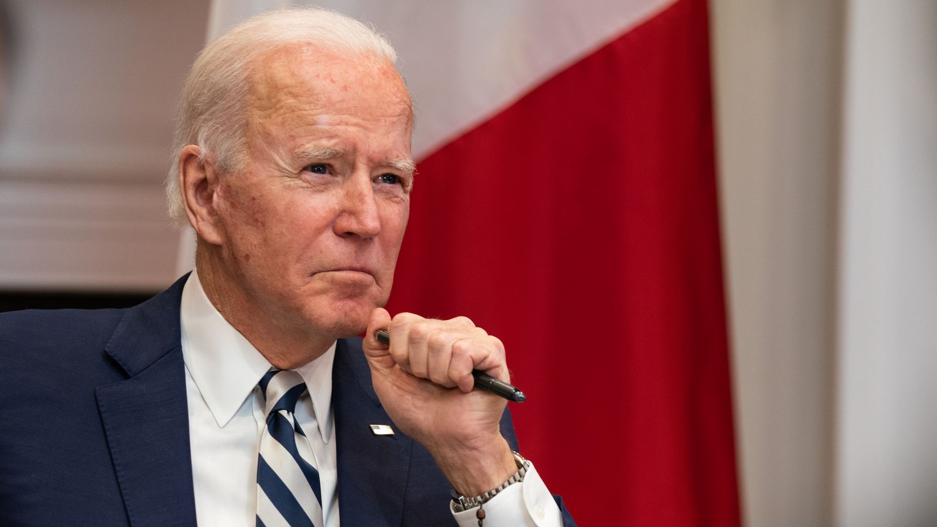 President Joe Biden holding a pen and looking thoughtful