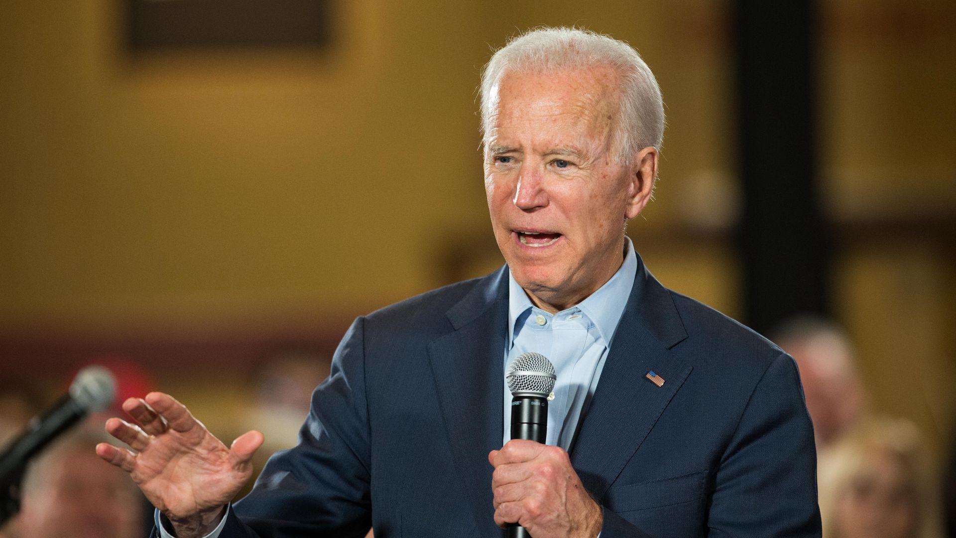 In this image, Biden stands and holds a microphone.