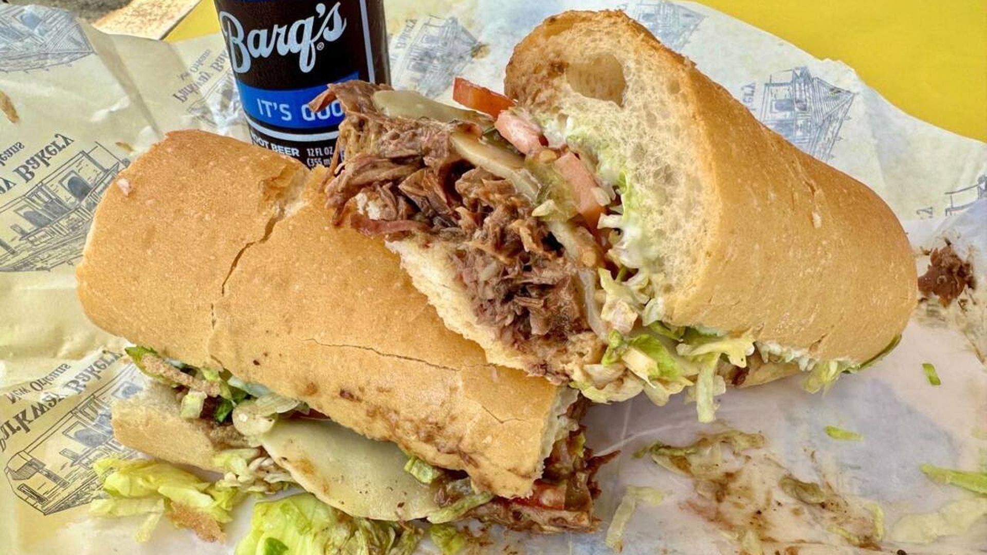 Photo shows a roast beef poboy with a Barq's root beer in the back.