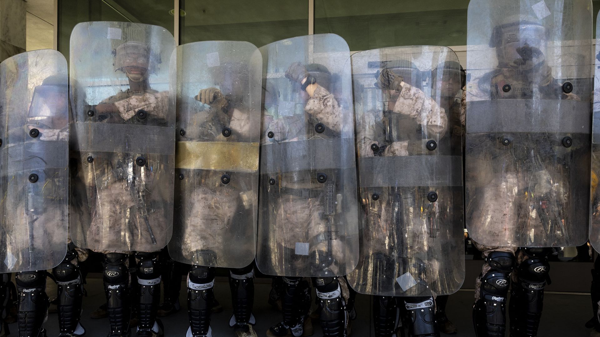 National Guard personnel stand shoulder-to-shoulder holding shields.