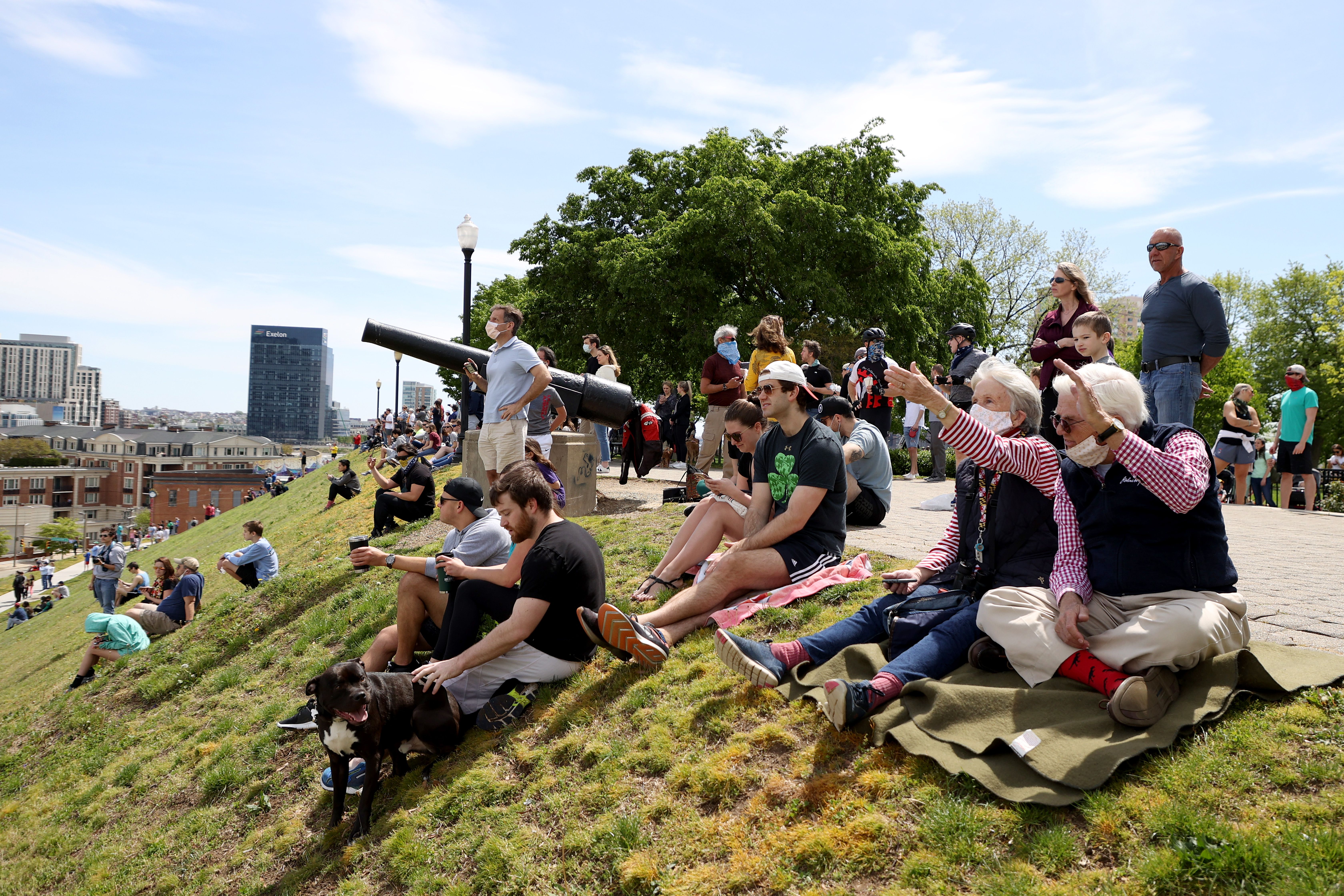 In this image, people sit on a hill and point at the planes 