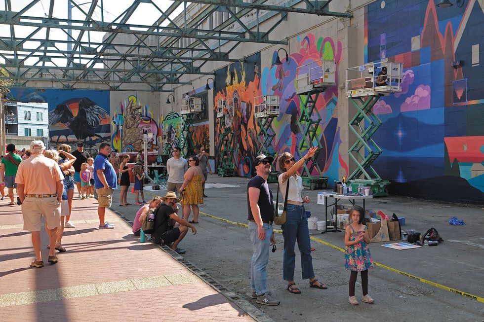 People stand and point at murals.