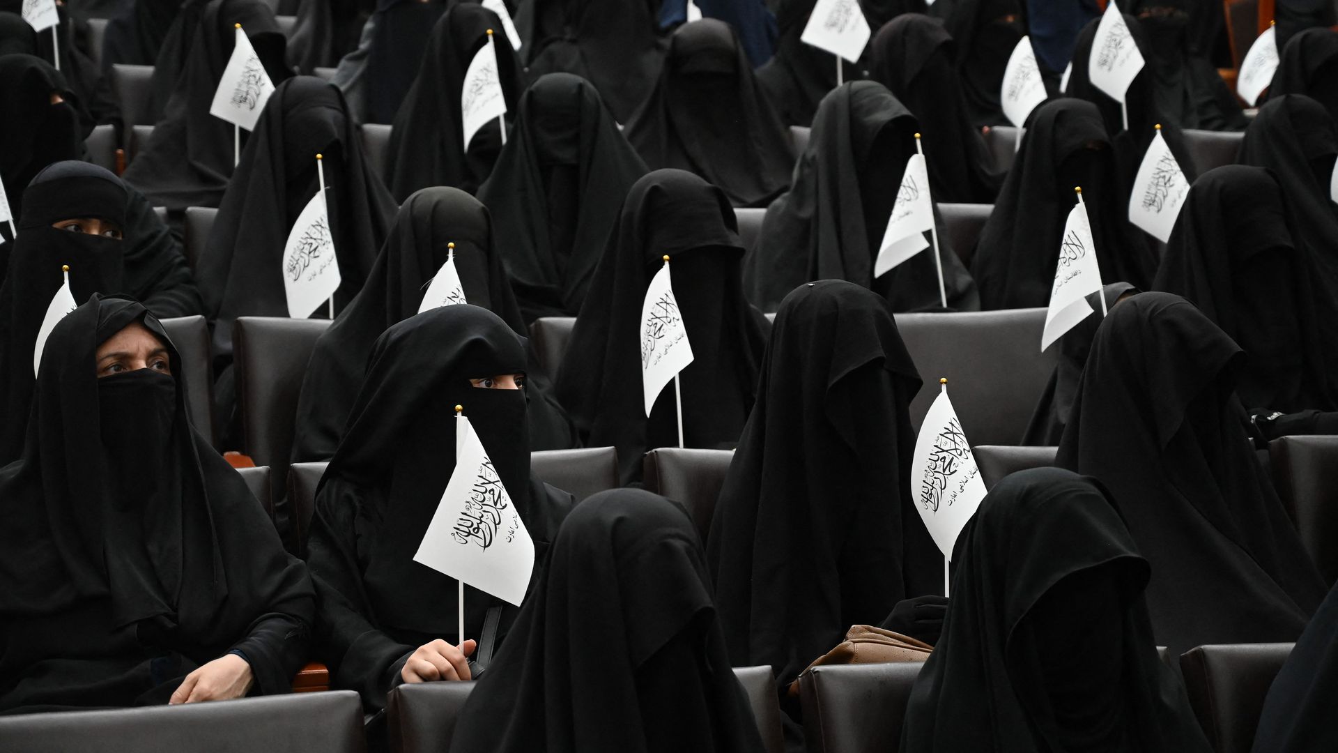 Veiled students hold Taliban flags as they listen women speakers before a pro-Taliban rally at the Shaheed Rabbani Education University in Kabul on September 11