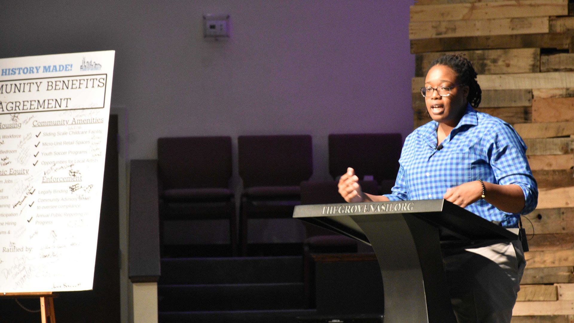 Odessa Kelly speaking on stage in a blue checkered shirt