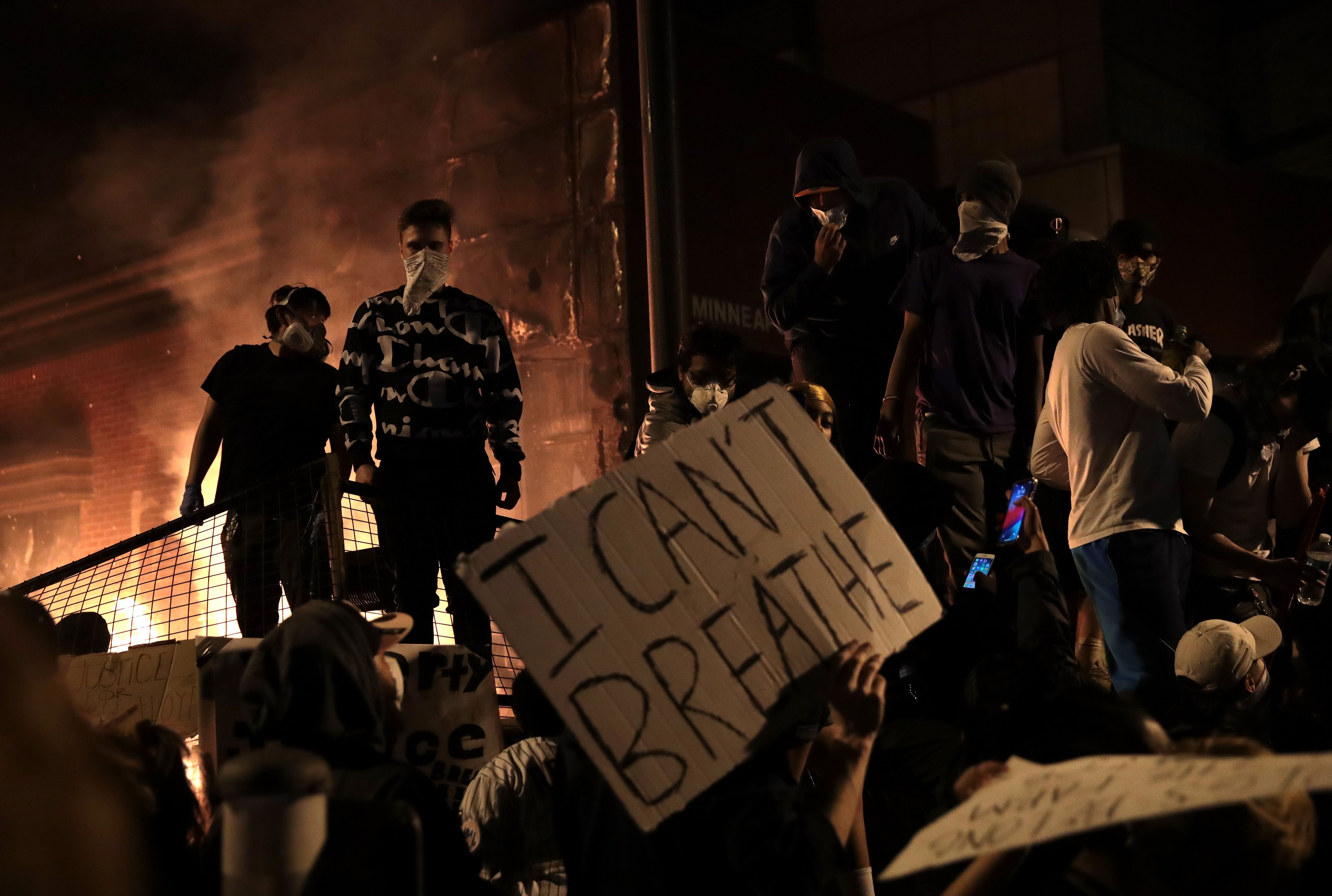 Protesters stand in front of the 3rd precinct police building as it burns during a protest on May 28