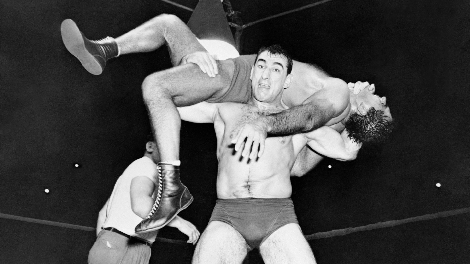 Two wrestlers compete in a match in black and white. 