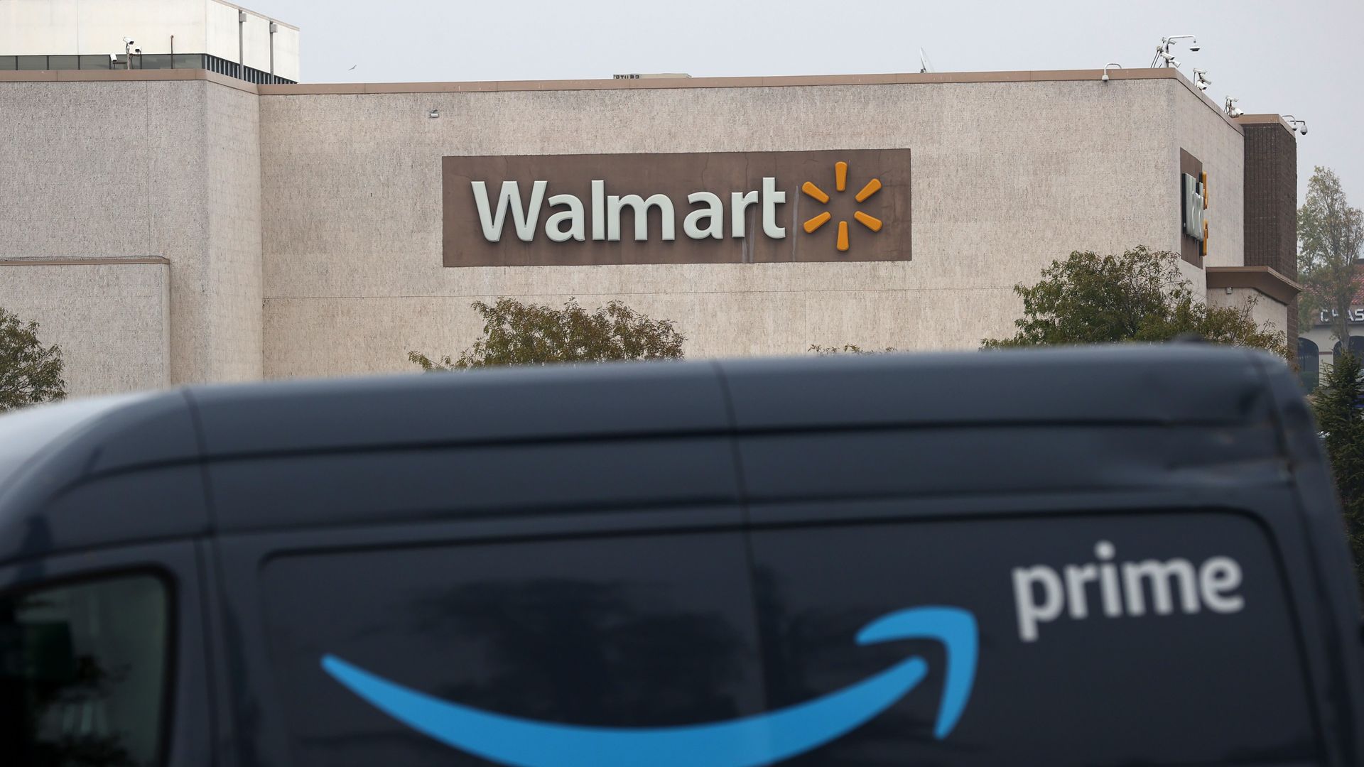 Amazon Prime delivery van in front of a Walmart storefront 