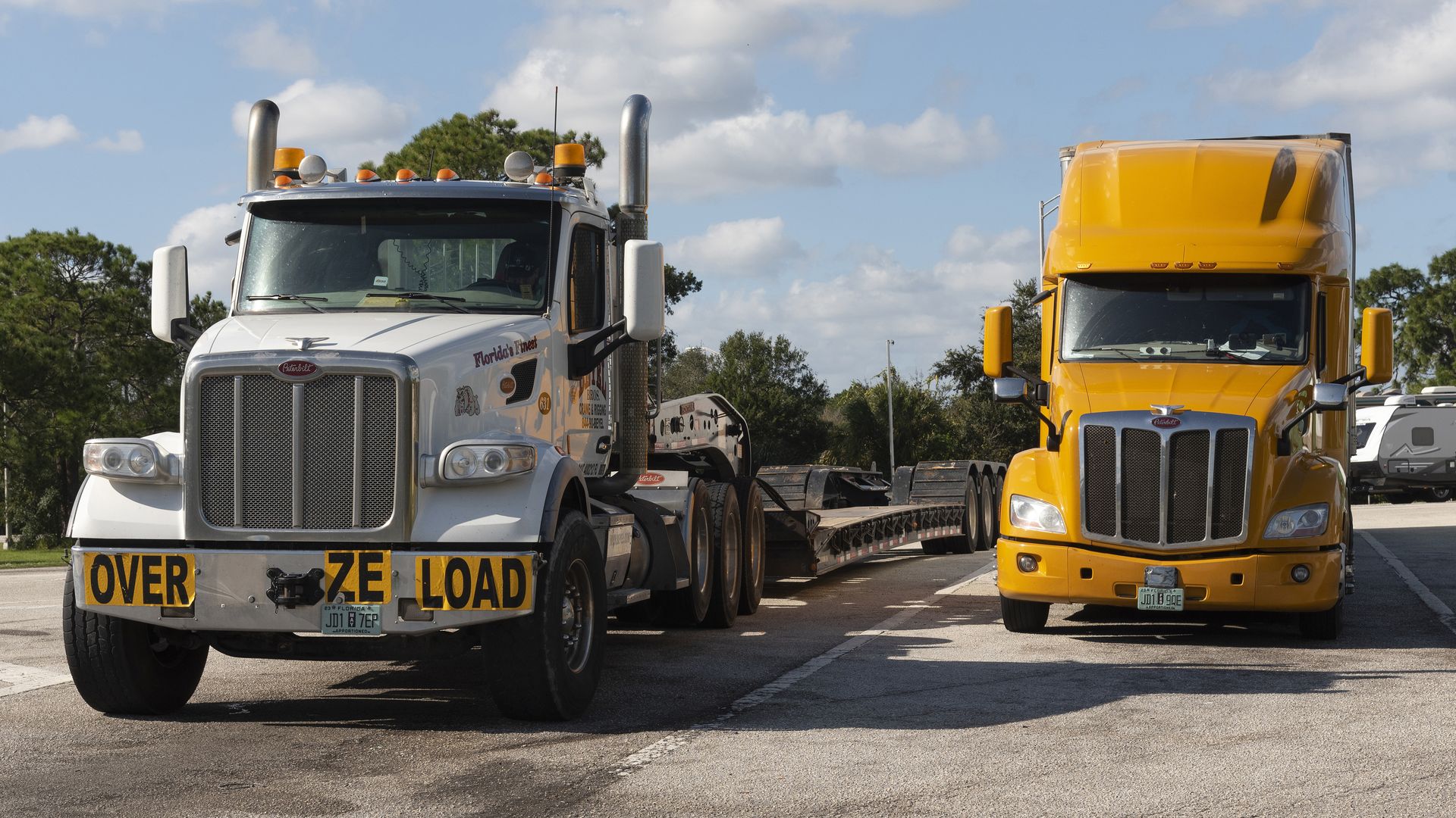 Two tractor trailers parked in a lot. 