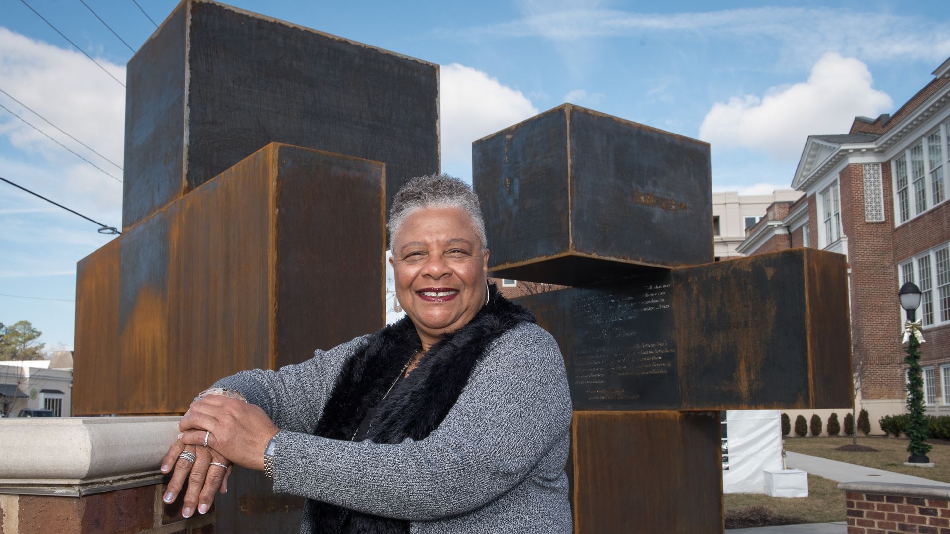 A pic of Jane Cooper Johnson smiling in front of a steel sculpture.