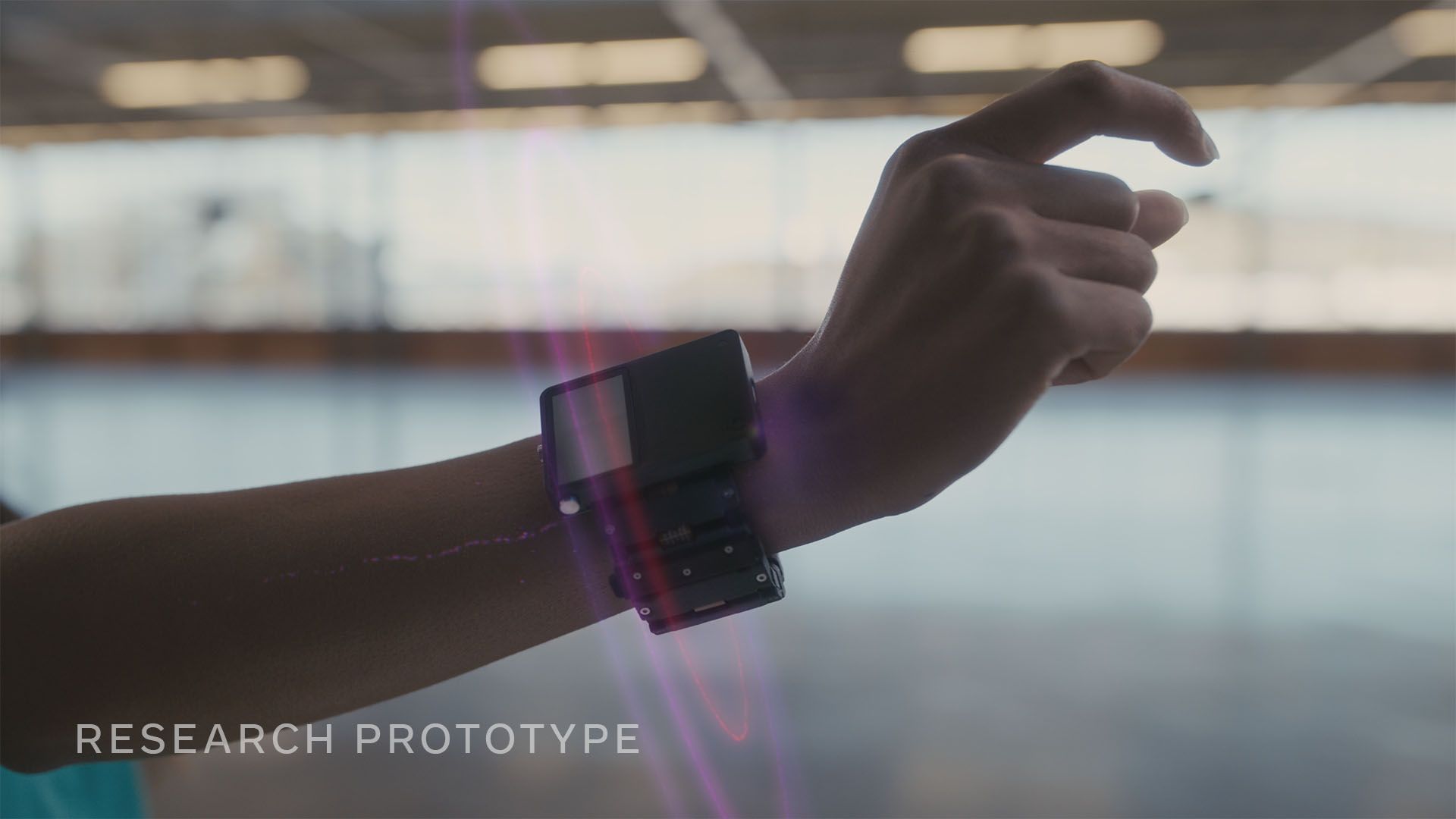 Photo of prototype Facebook wristband that reads nerve impulses, on a person's arm with the finger pointing