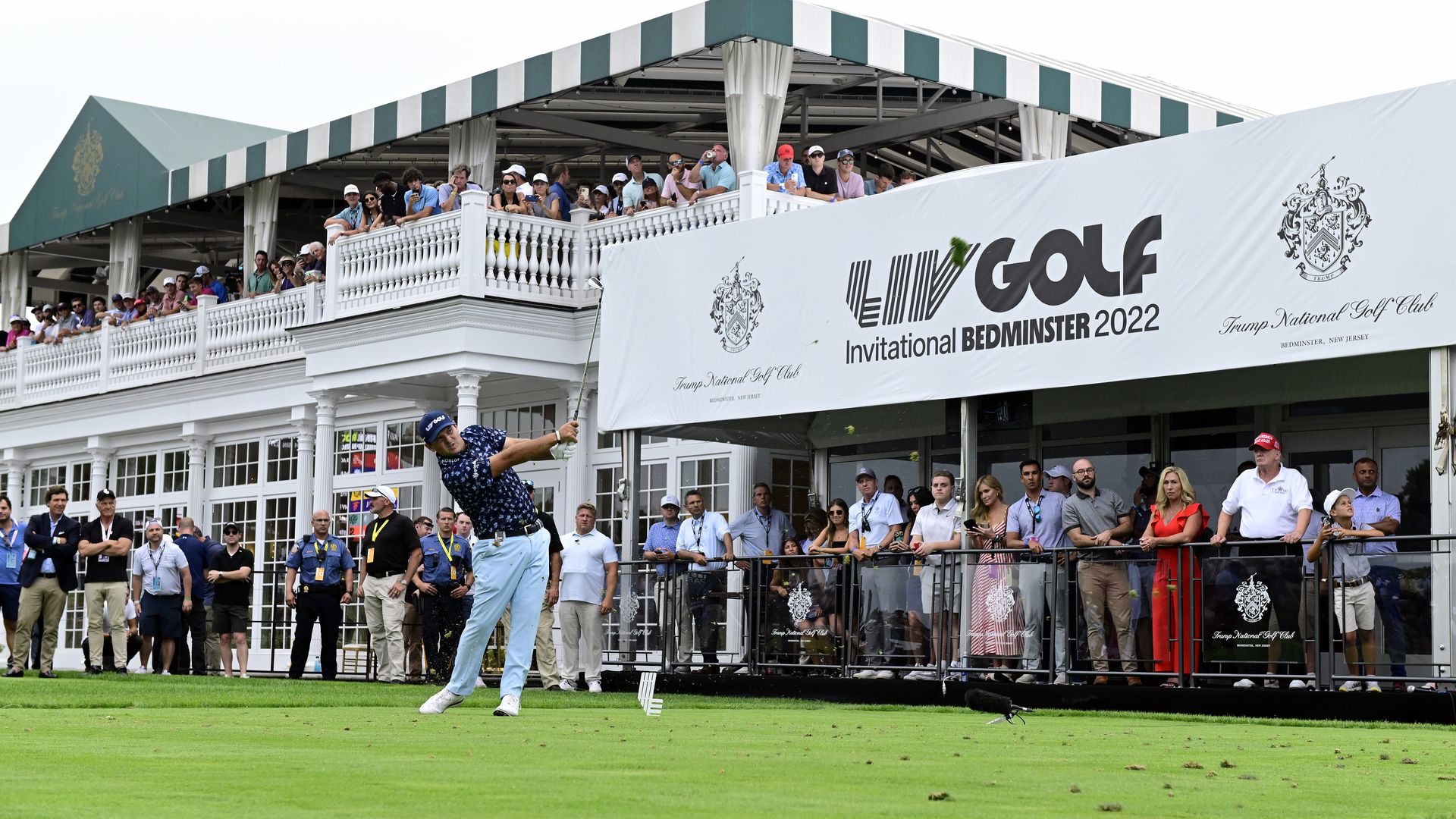 Photo of people watching a golfer swing, with a sign saying LIV Golf hanging in the back