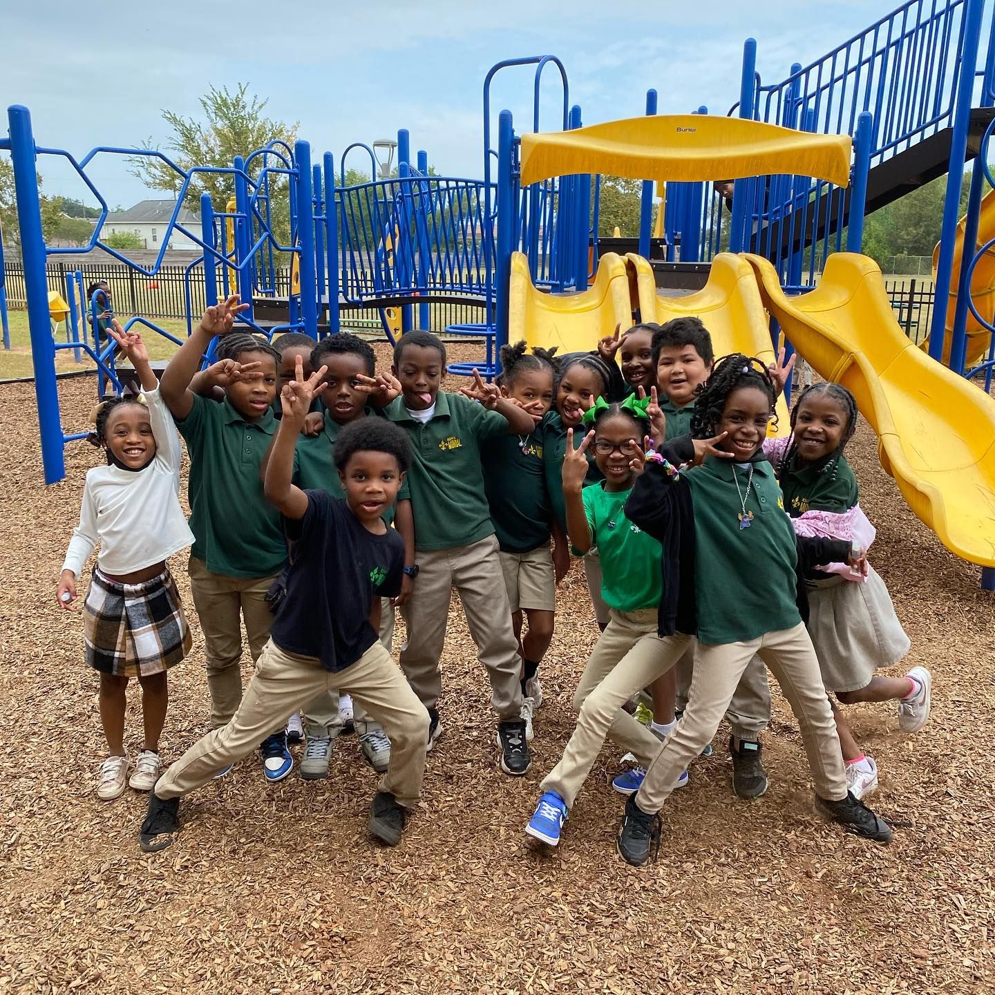 Photo shows happy children in school uniforms in front of playground equipment