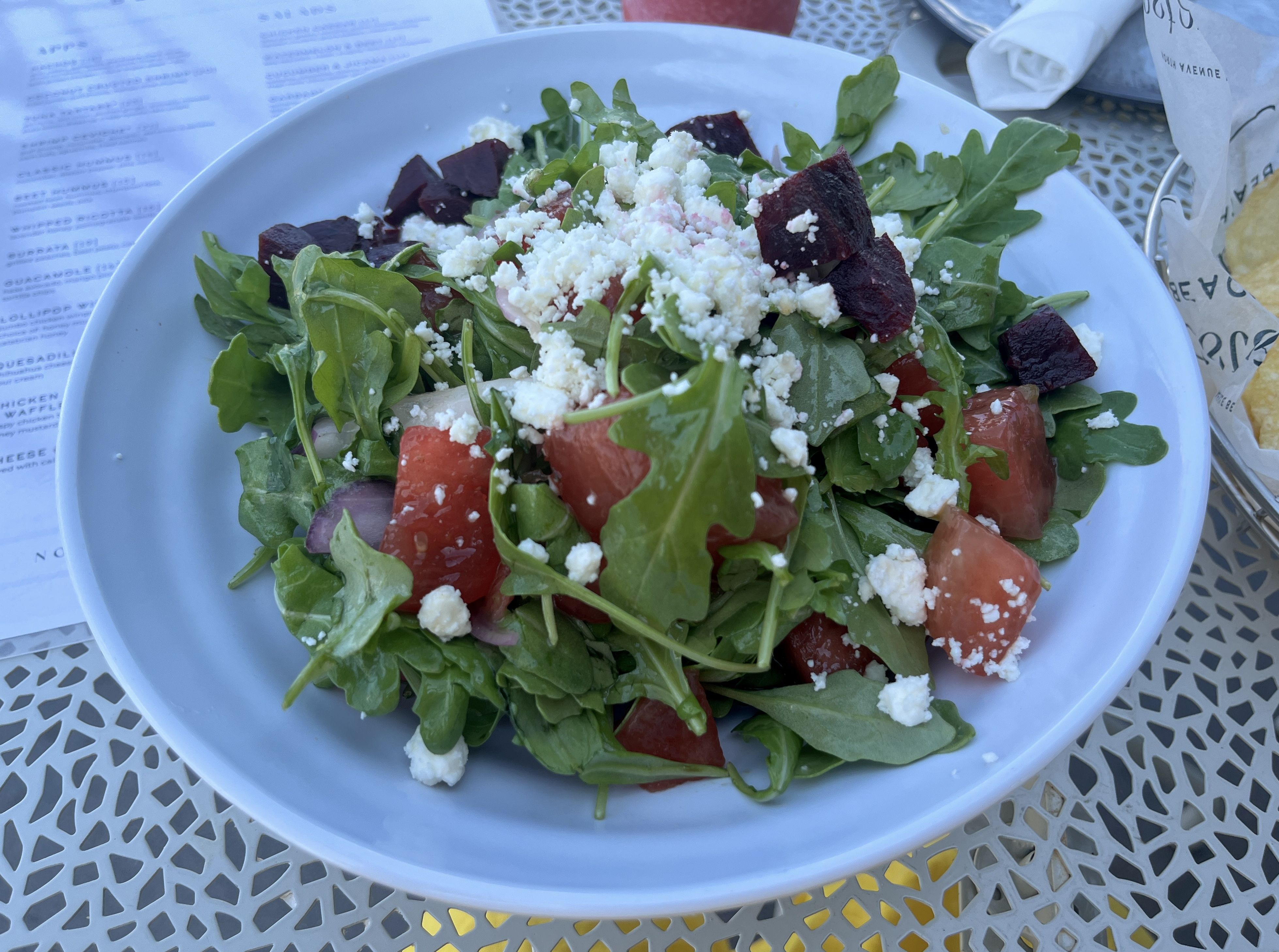 Arugula salad with watermelon, beets and feta in white bowl.