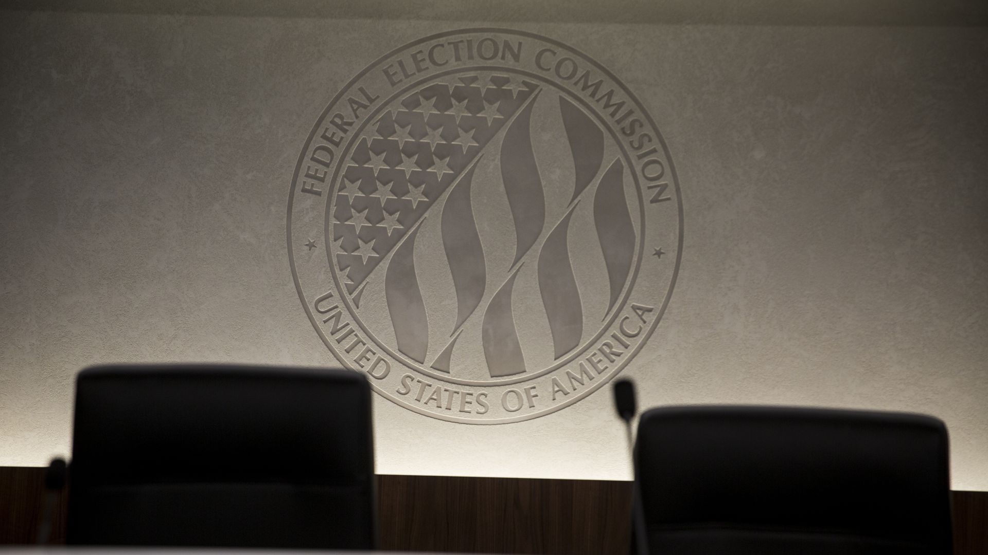 The federal election commission logo behind a set of empty chairs.