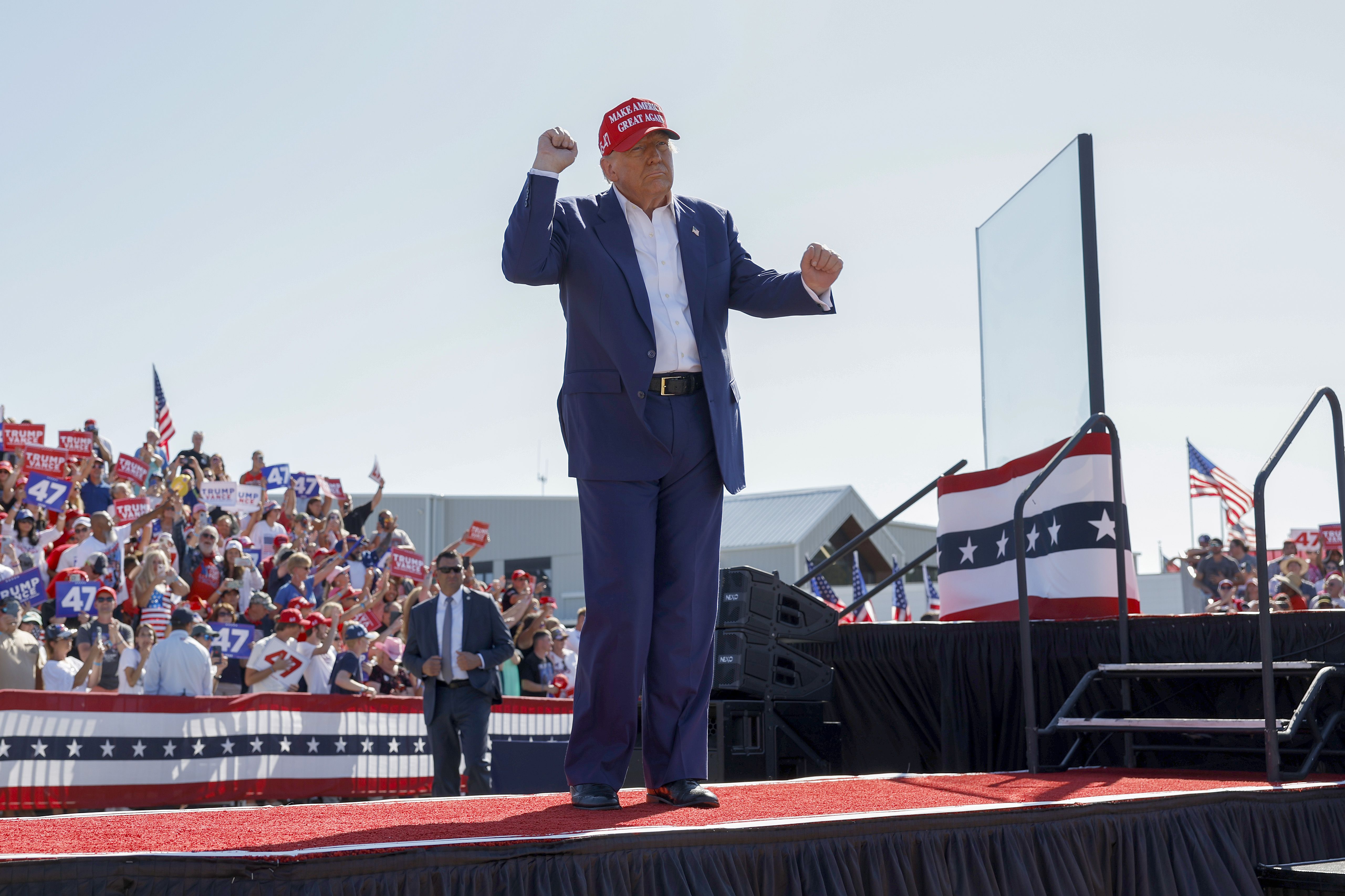 Trump walks off stage with his fist in the air and a crowd of audience members behind him