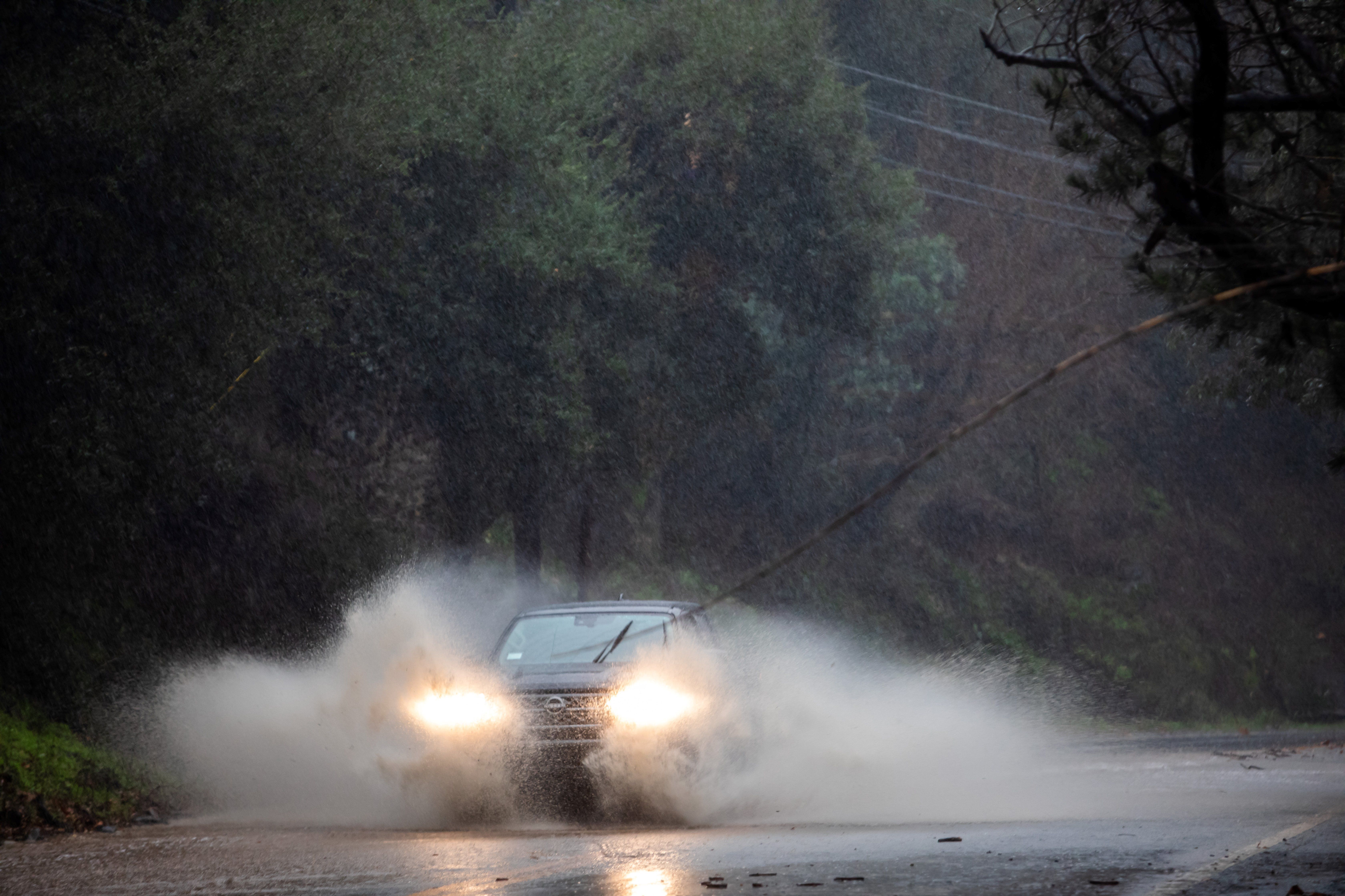 A car drives through a flooded road in Topanga, California, on February 4, 2024. The US West Coast was getting drenched on February 1 as the first of two powerful storms moved in, part of a "Pineapple Express" weather pattern that was washing out roads and sparking flood warnings. The National Weather Service said "the largest storm of the season" would likely begin on February 4.