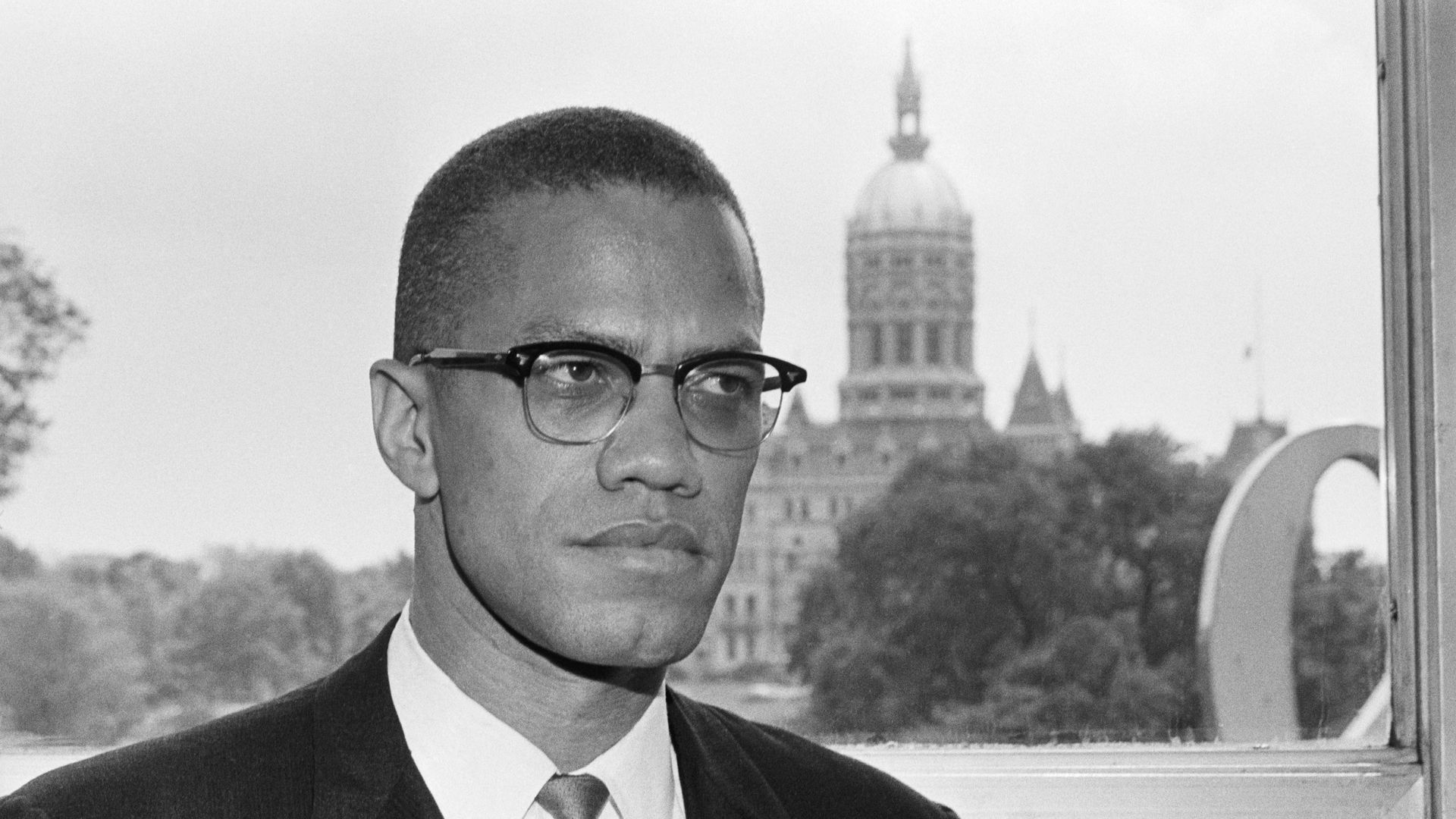 Malcolm X is shown with the dome of the Connecticut Capitol behind him as he arrived in Hartford for a two day visit.