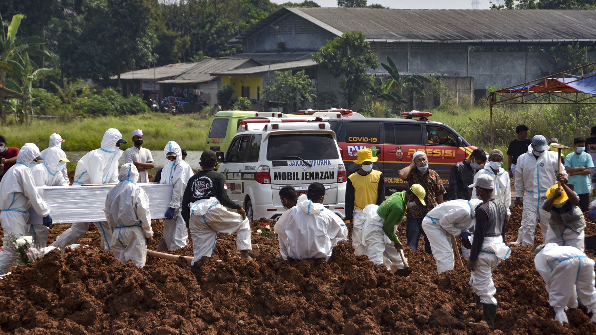 Workers bury the bodies of Covid-19 coronavirus victims at the Pedurenan public cemetery in Bekasi, West Java, on July 7