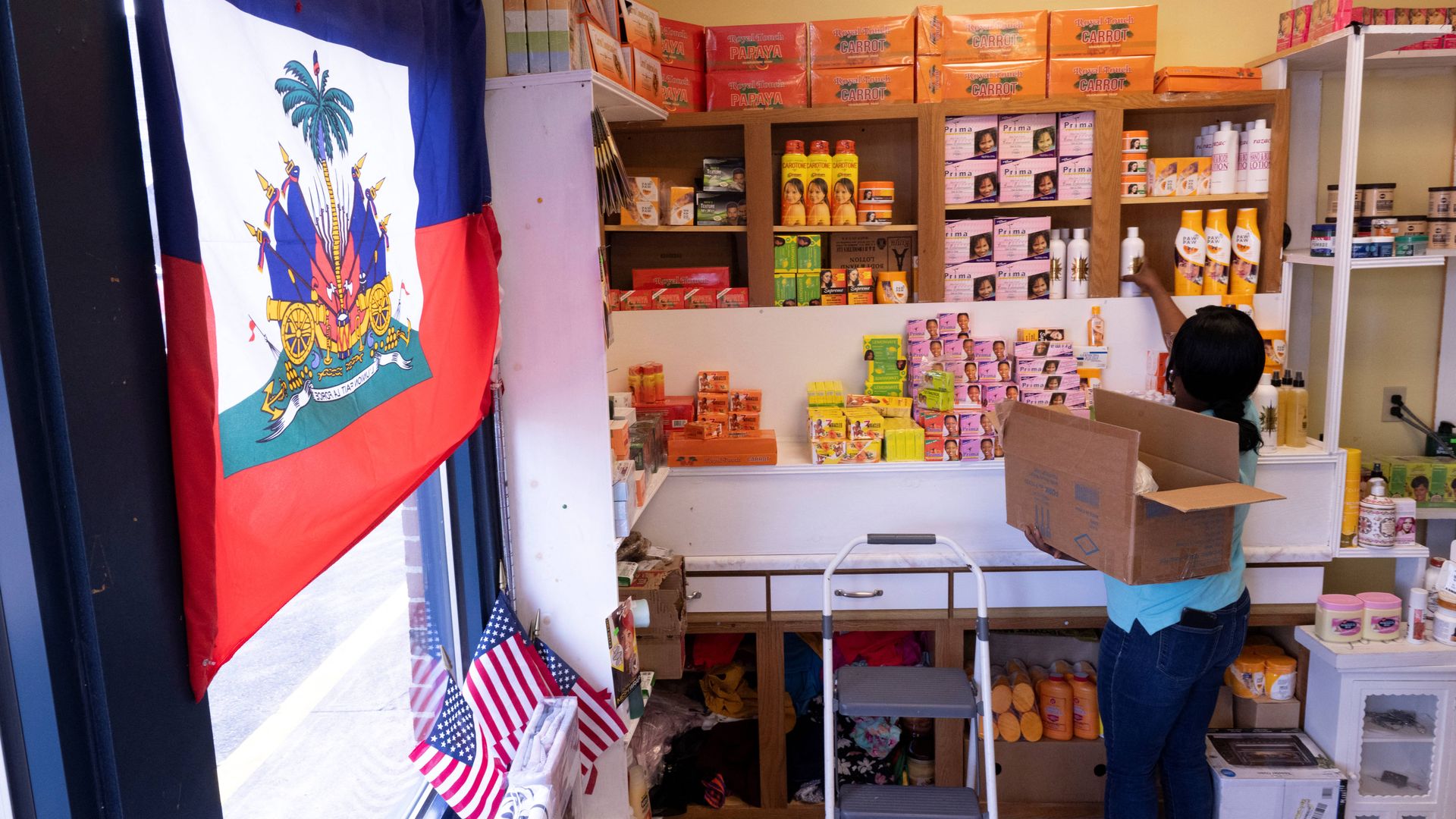 Creations Market shop owner Philomene Philostin, a naturalized US citizen of Haitian origin, shelves merchandise in her store that caters mainly to Haitian residents in Springfield, Ohio, on September 13