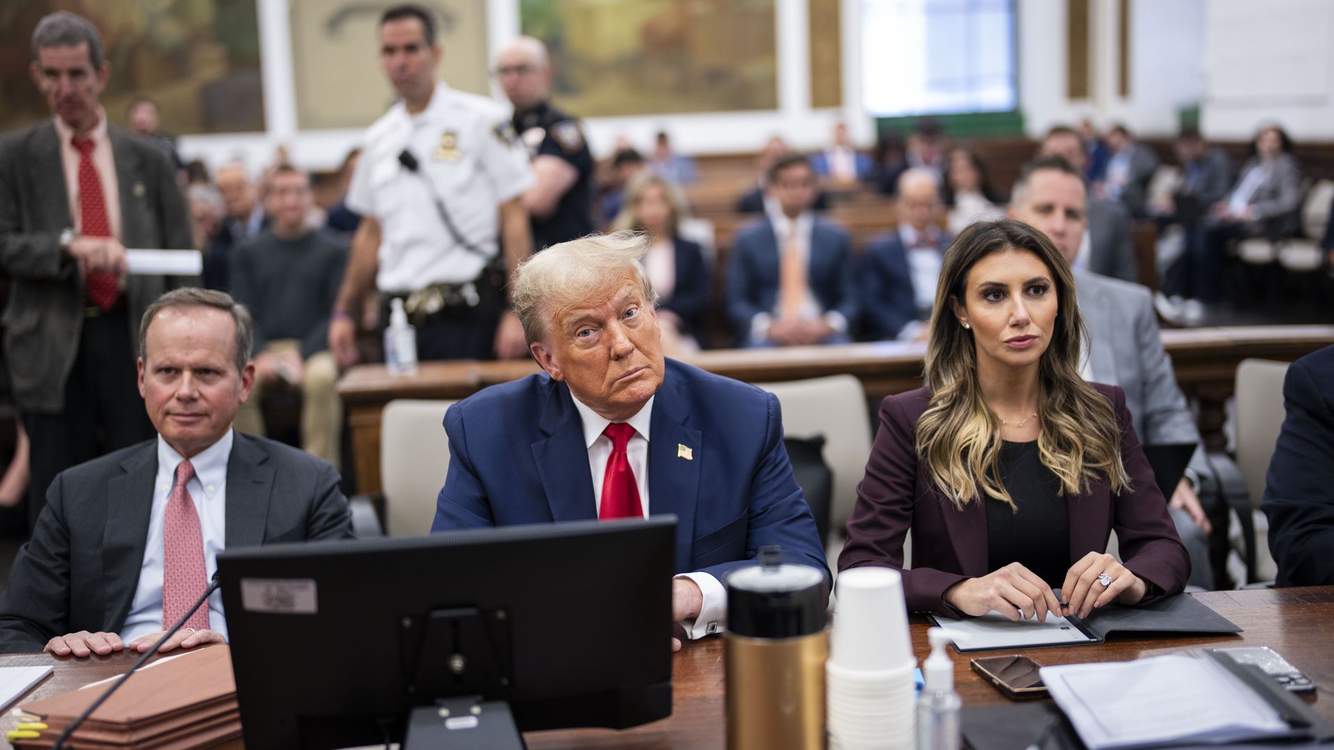 Donald Trump sits in a courtroom between his two attorneys, Christopher M. Kise and Alina Habba.