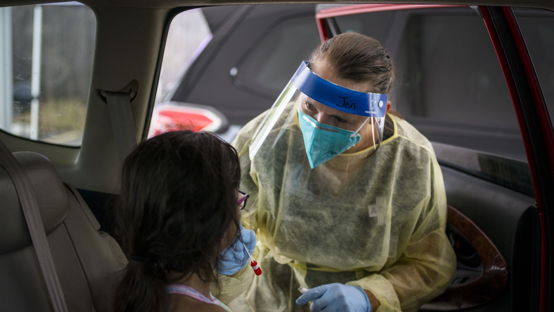 A photo of a woman administering a COVID test.