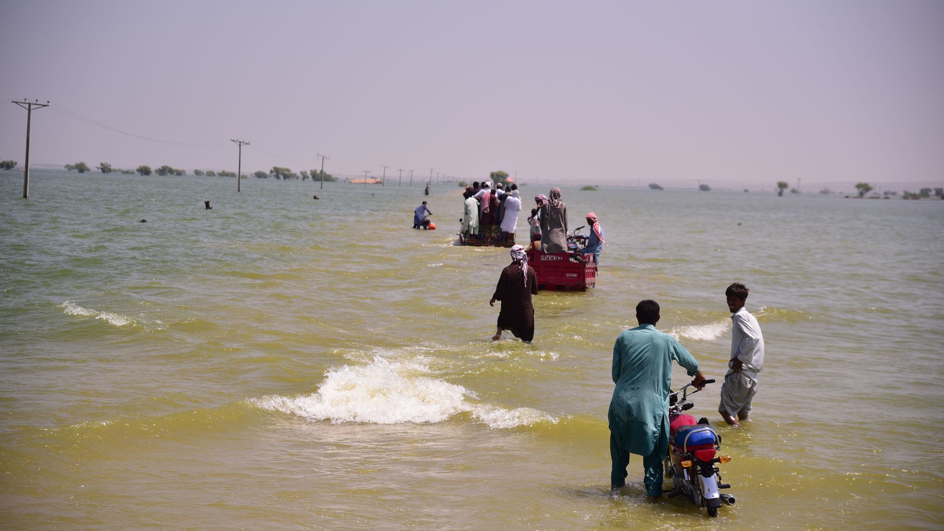 Flooding survivors from monsoon rains in Pakistan leave their homes on Sept. 9, 2022.