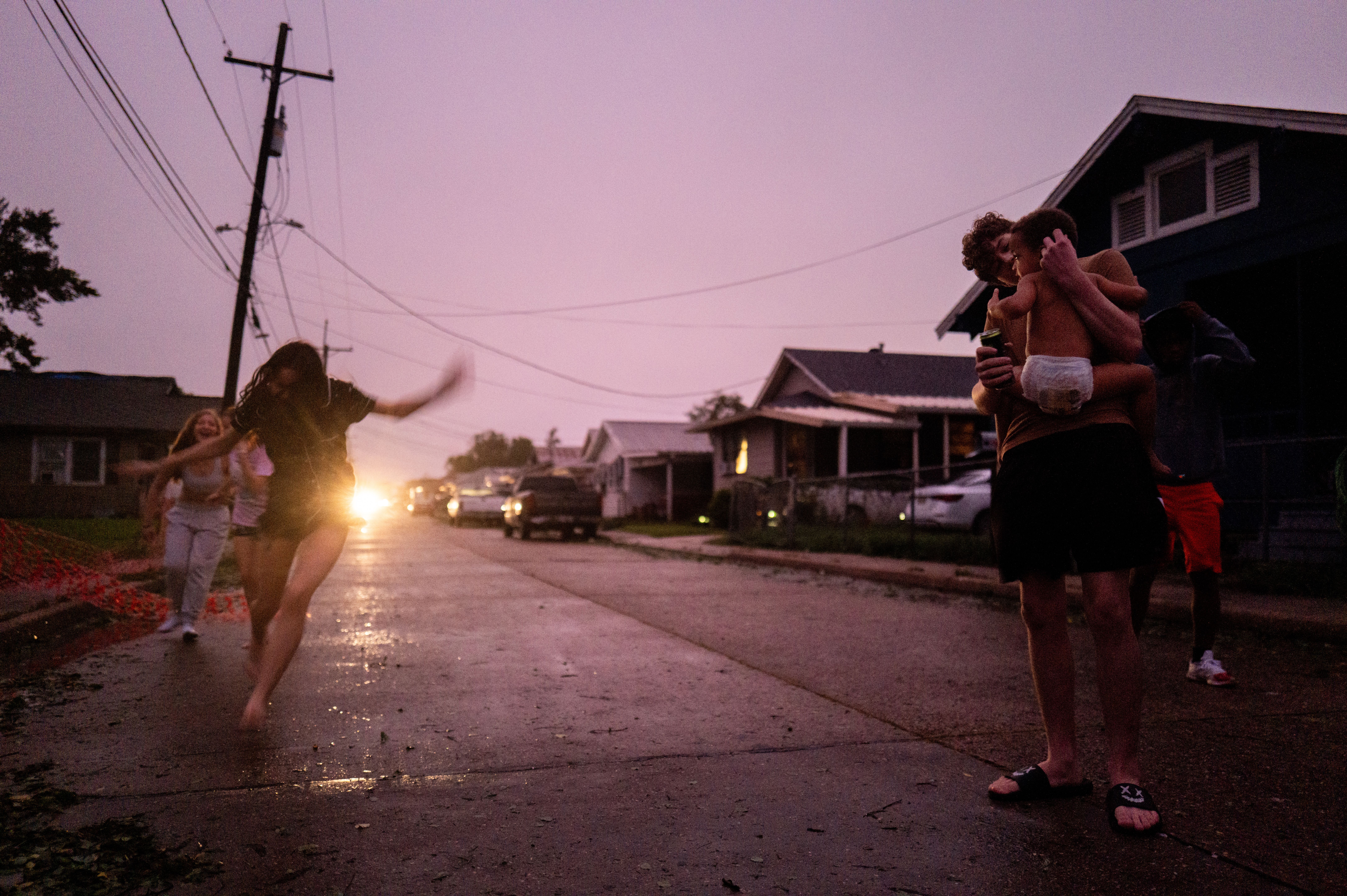 A family plays in the street on a darkened block.