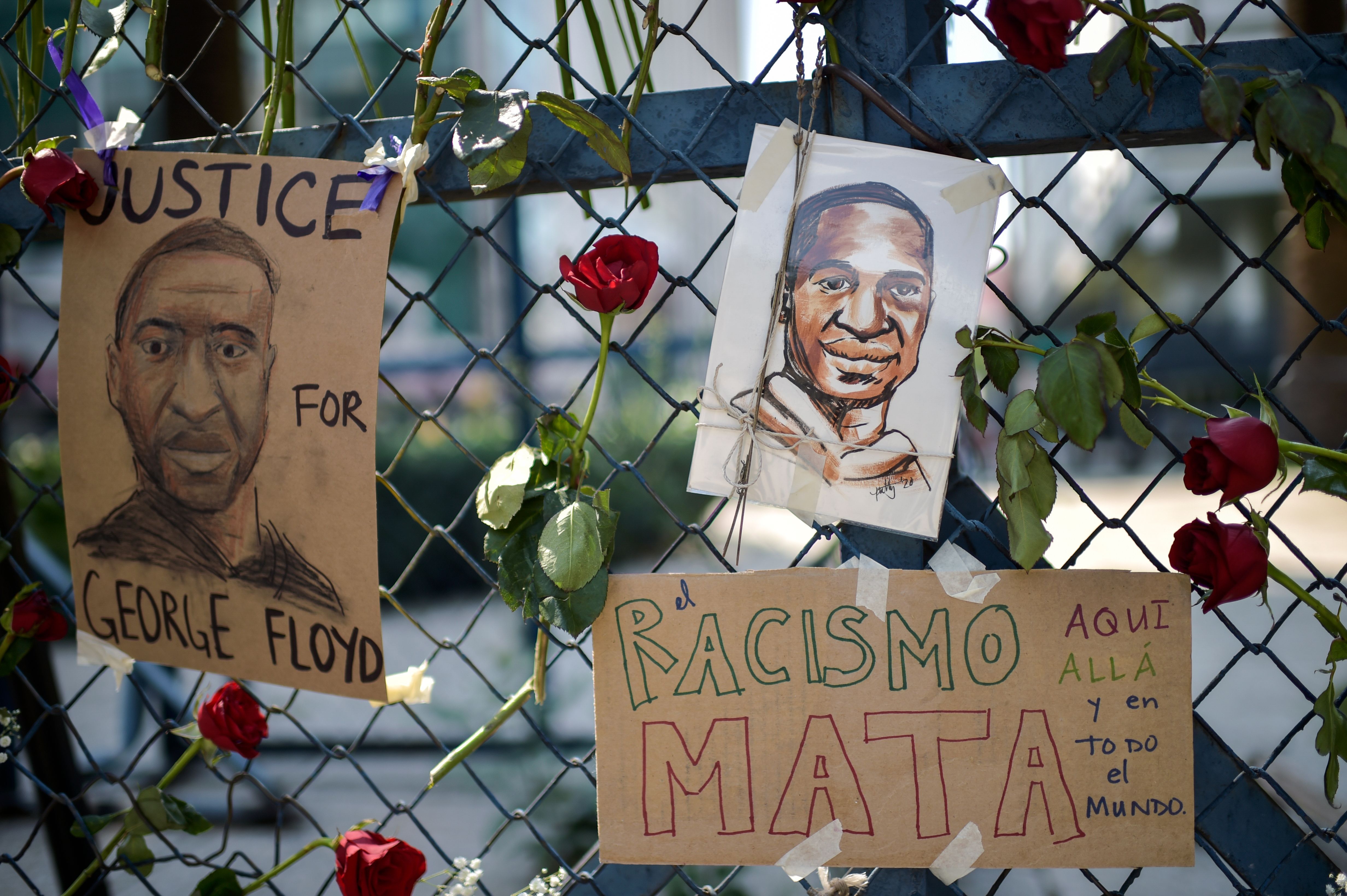 Hand drawn portraits of George Floyd or hung on a gate in Mexico City and and a sign reading "Racism kills, here, there, and all over the world"