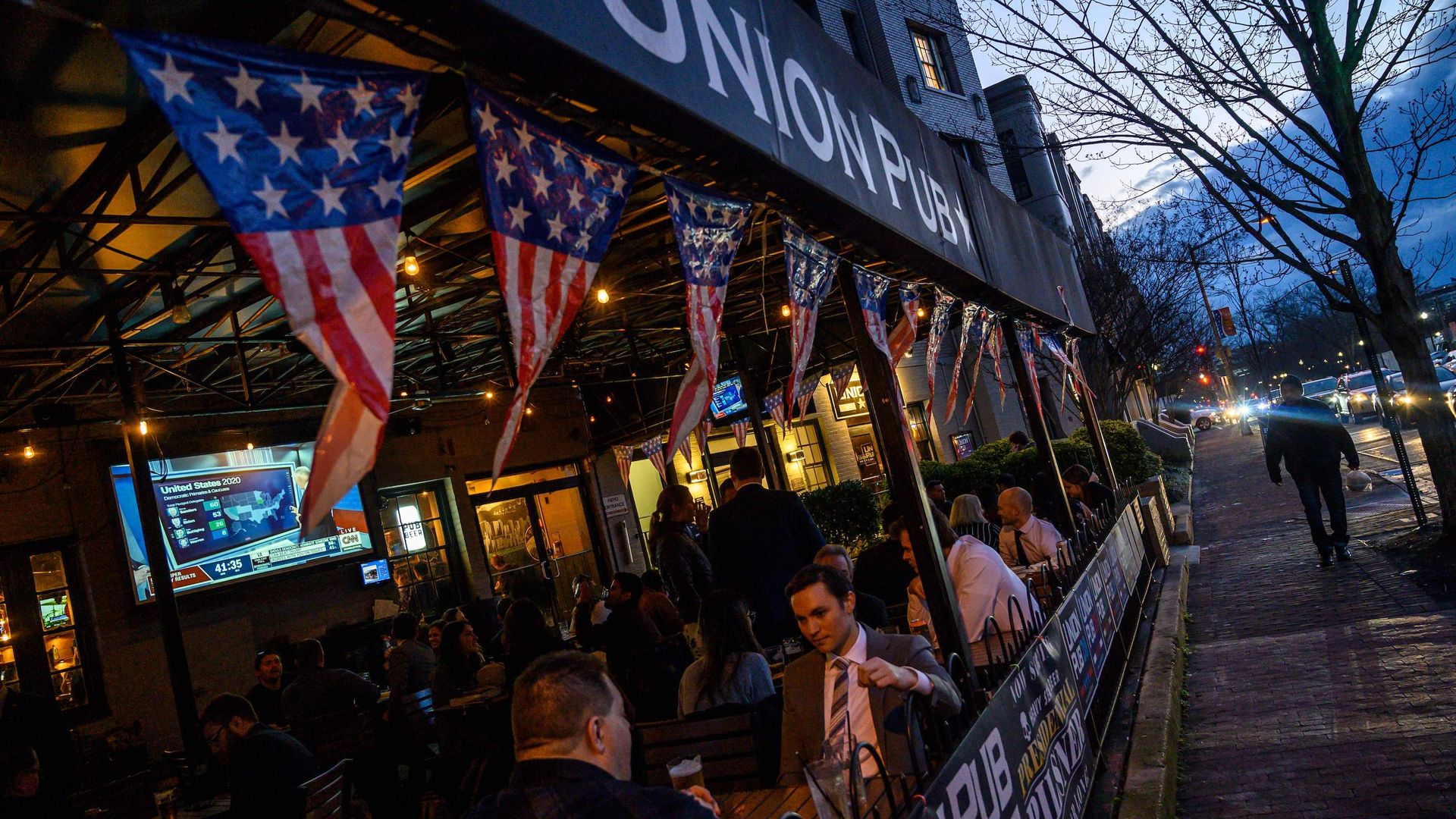 People sit on the outdoor patio at Union Pub in DC with American flags hanging