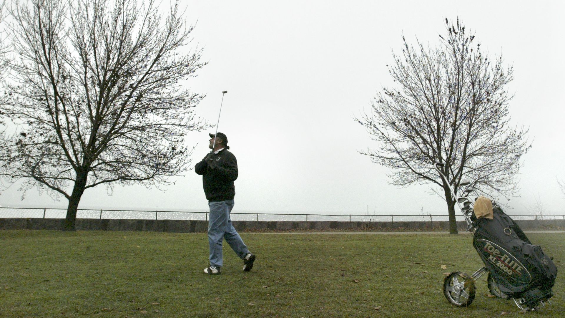 A photo of a man playing golf in winter. 