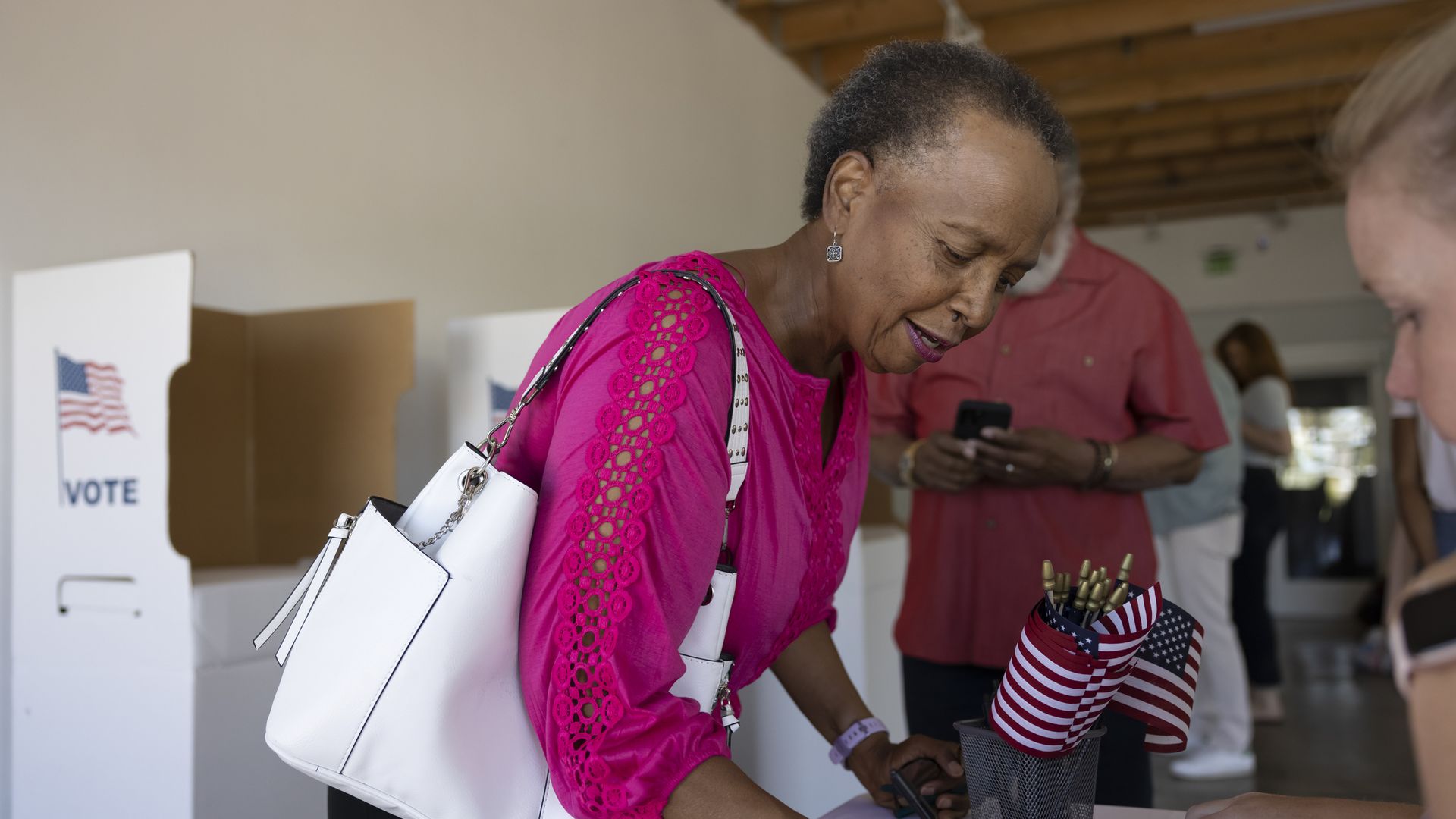 A woman is signing something. She is in a voting place.