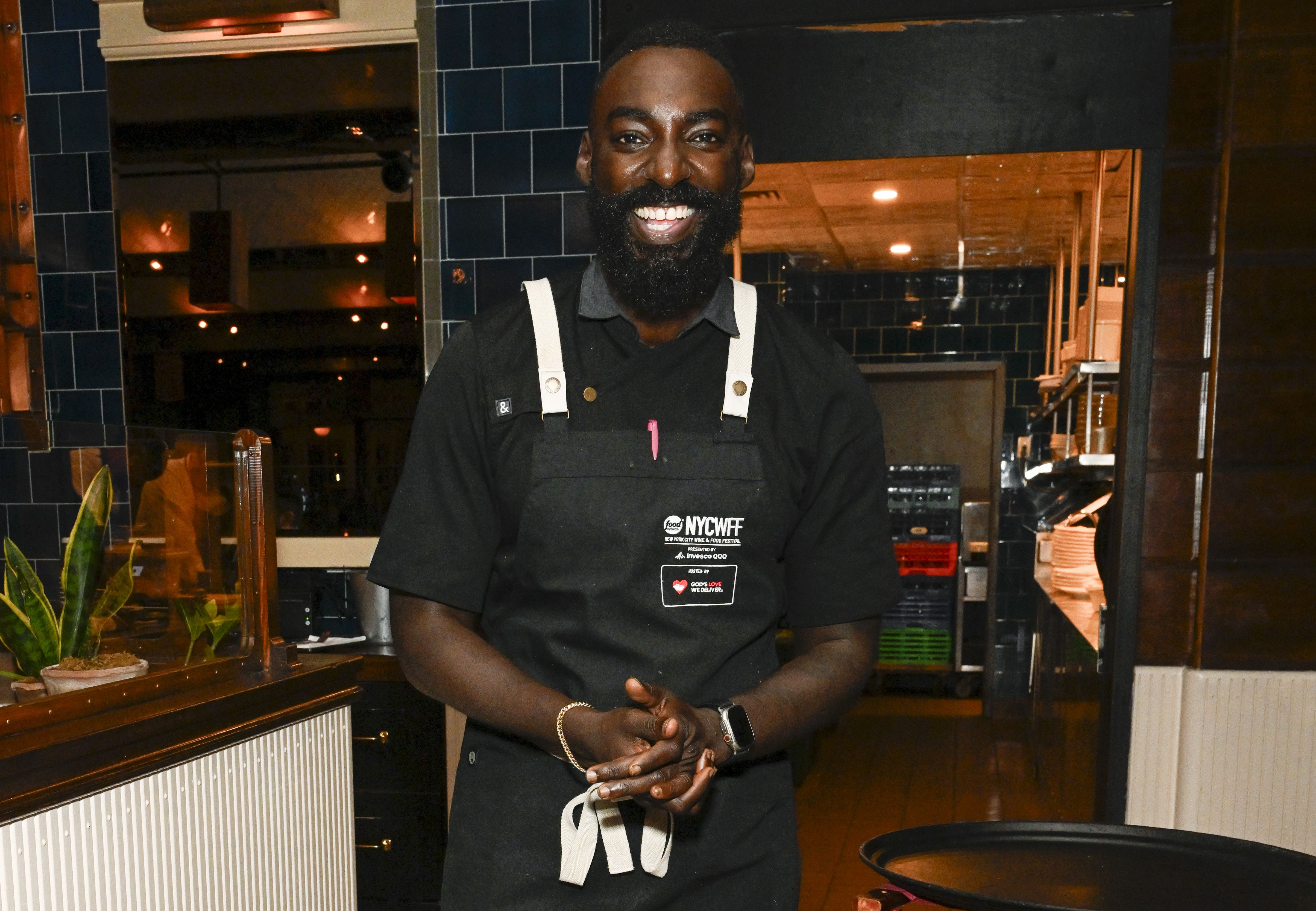 Chef Eric Adjepong in a black apron and t-shirt at an event in NYC